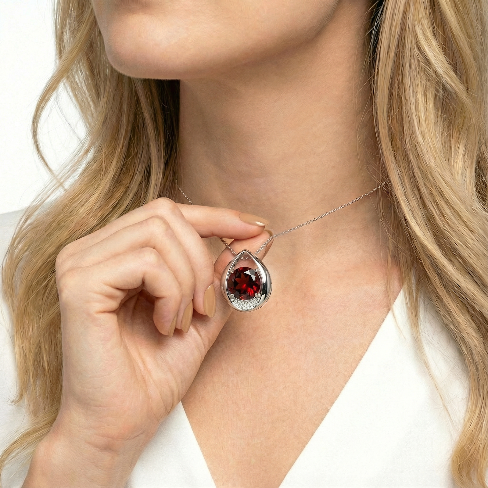 Model holding the sterling silver round cut simulated garnet pendant to show its scale and teardrop halo.