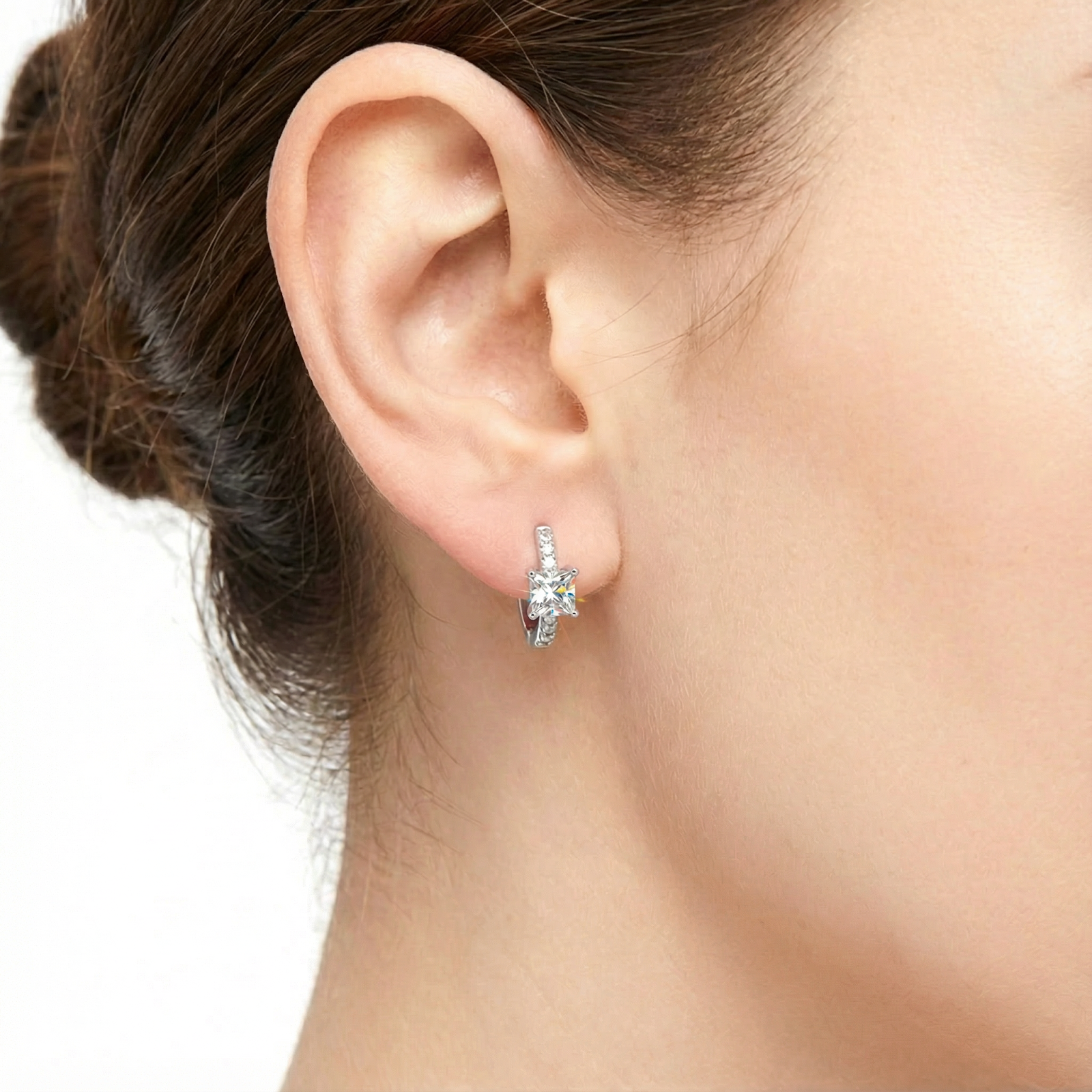 Close-up of a princess-cut simulated diamond and S925 sterling silver huggie earring worn on an ear.