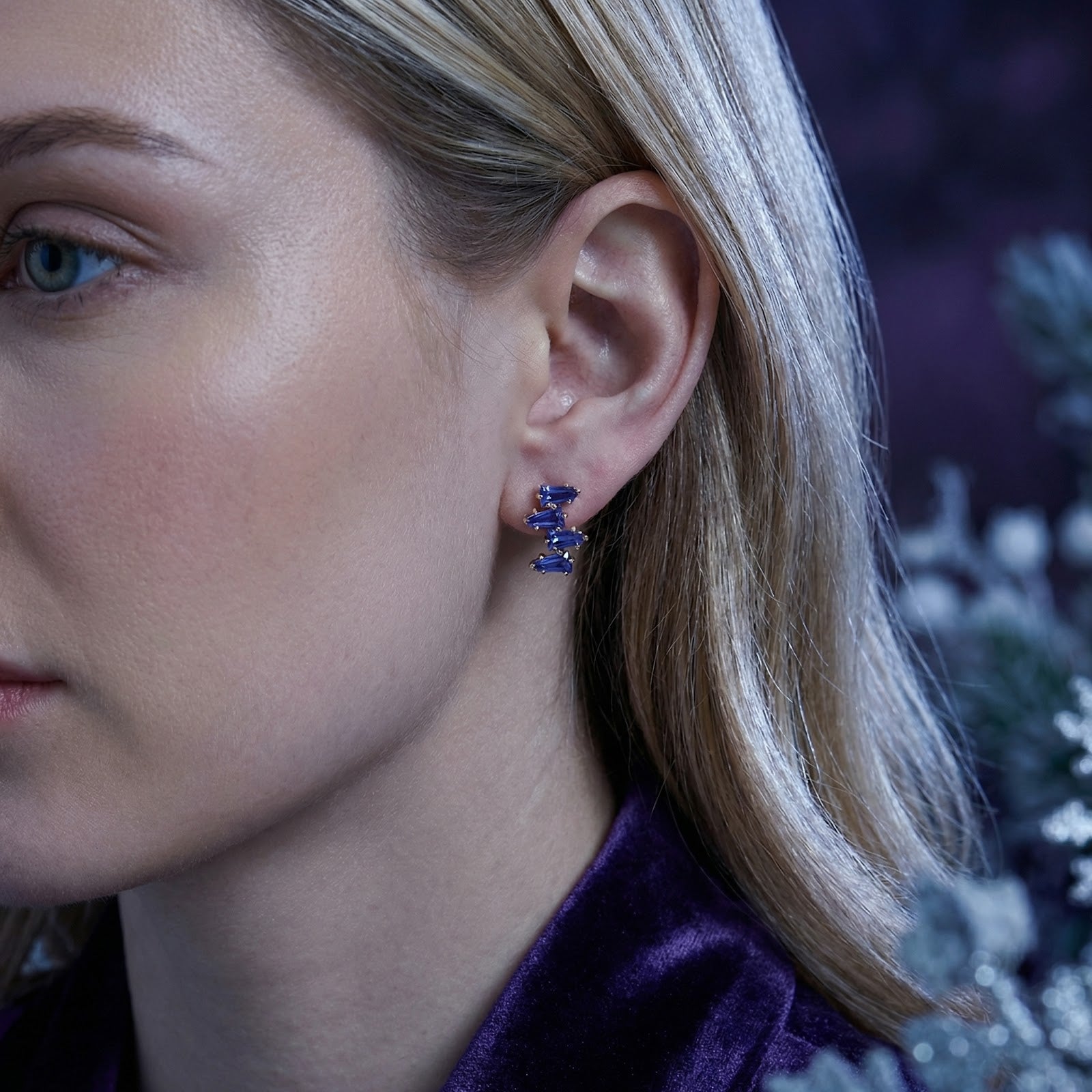 Close-up of a model wearing the Neriselle cluster earring in 18K gold vermeil with geometric simulated tanzanite.