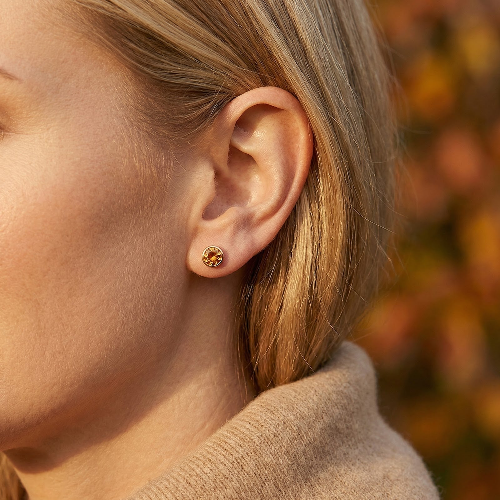 Side profile view of a woman wearing a gold vermeil Auriana stud earring with a round-cut honeyed topaz.