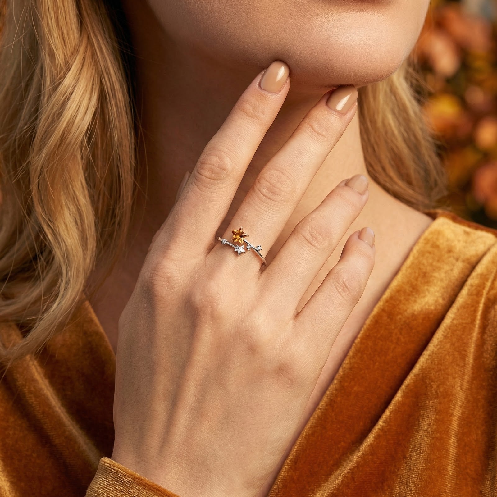 Woman wearing the silver Astralis Star ring with honey-colored simulated topaz, paired with a velvet dress.