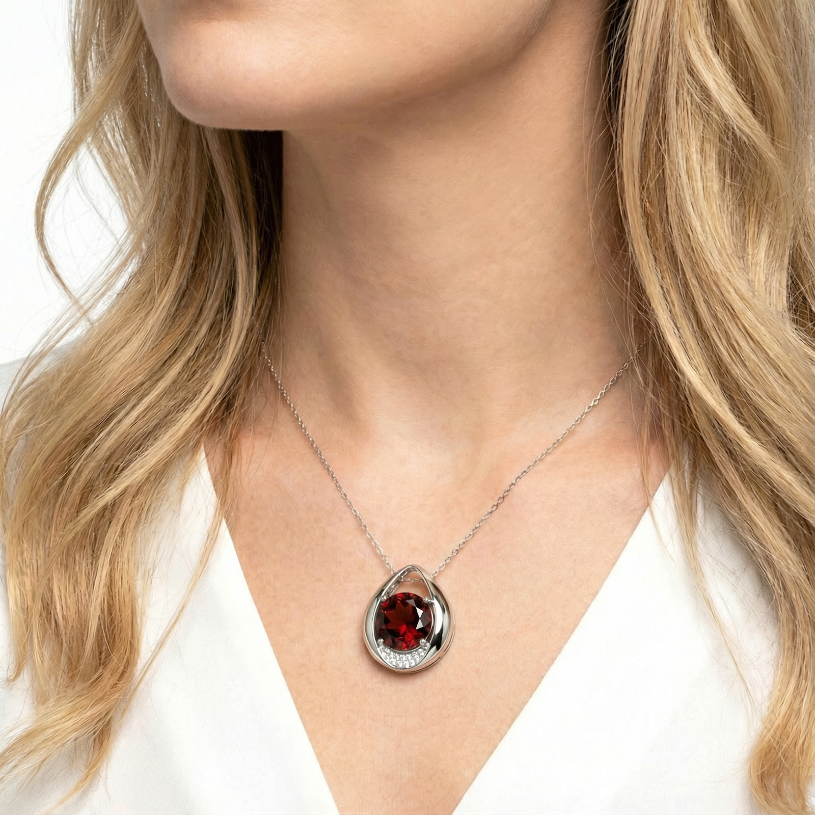 Blonde model wearing the sterling silver round cut simulated garnet teardrop necklace with a white top.