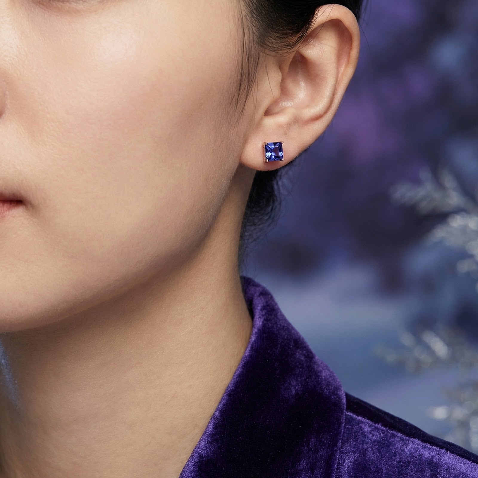 Woman wearing a princess-cut simulated tanzanite stud earring in 18K rose gold vermeil.