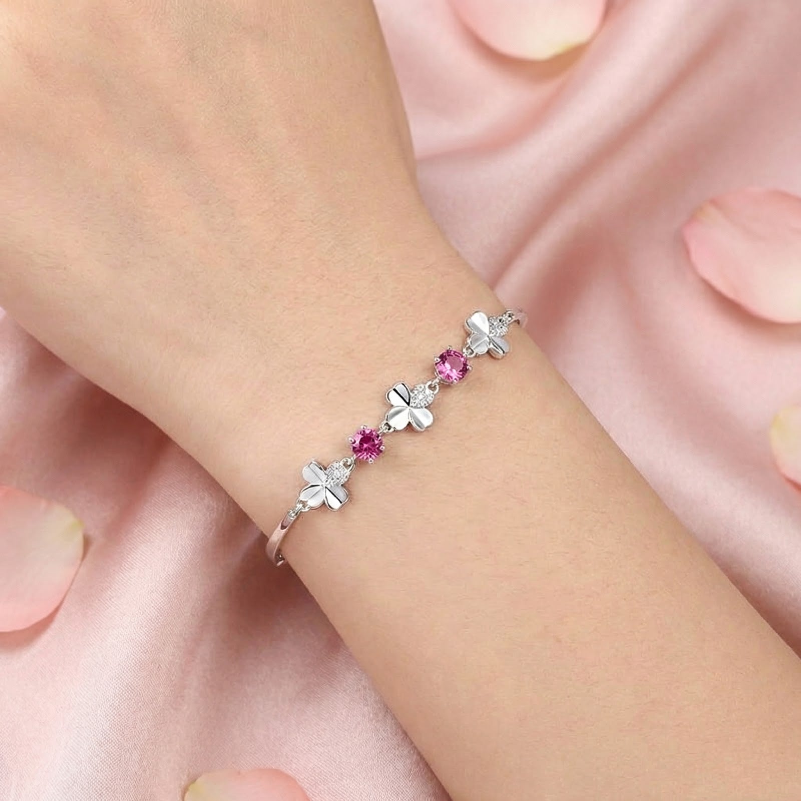 Close-up of the sterling silver clover bracelet with round pink tourmaline stones worn on a woman's wrist.