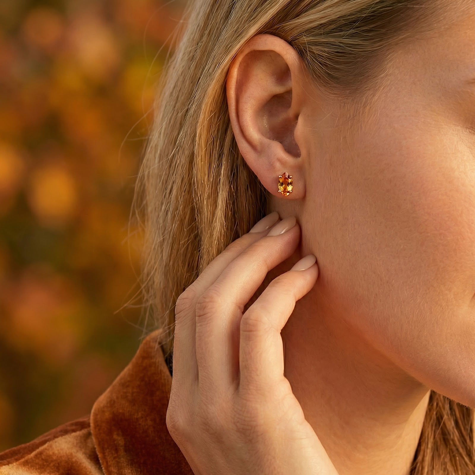 Side view of a woman wearing a marquise-cut golden simulated topaz earring in 18K gold vermeil.
