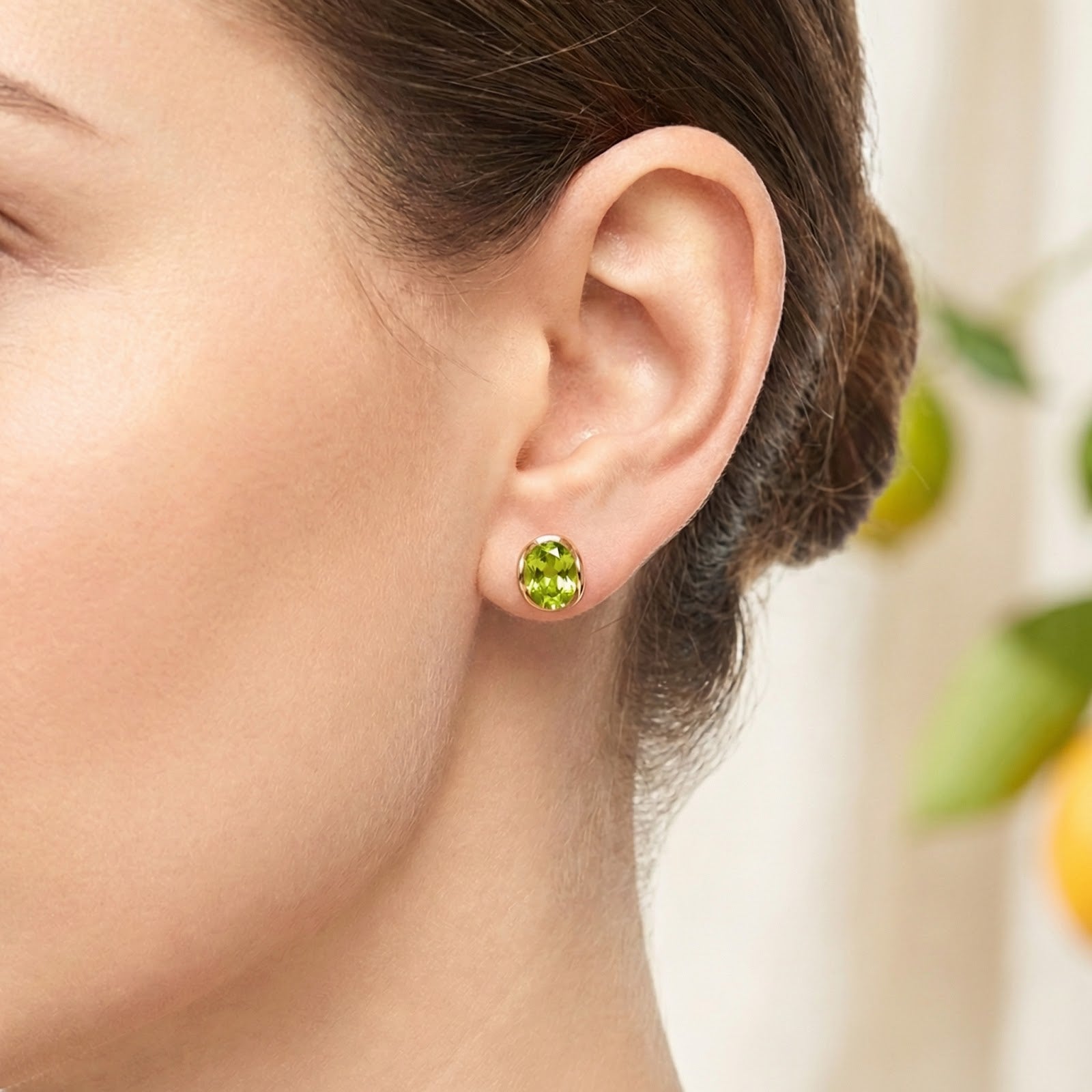 Close-up of the Veriselle oval simulated peridot stud earring in 18K gold vermeil worn on a model's ear.