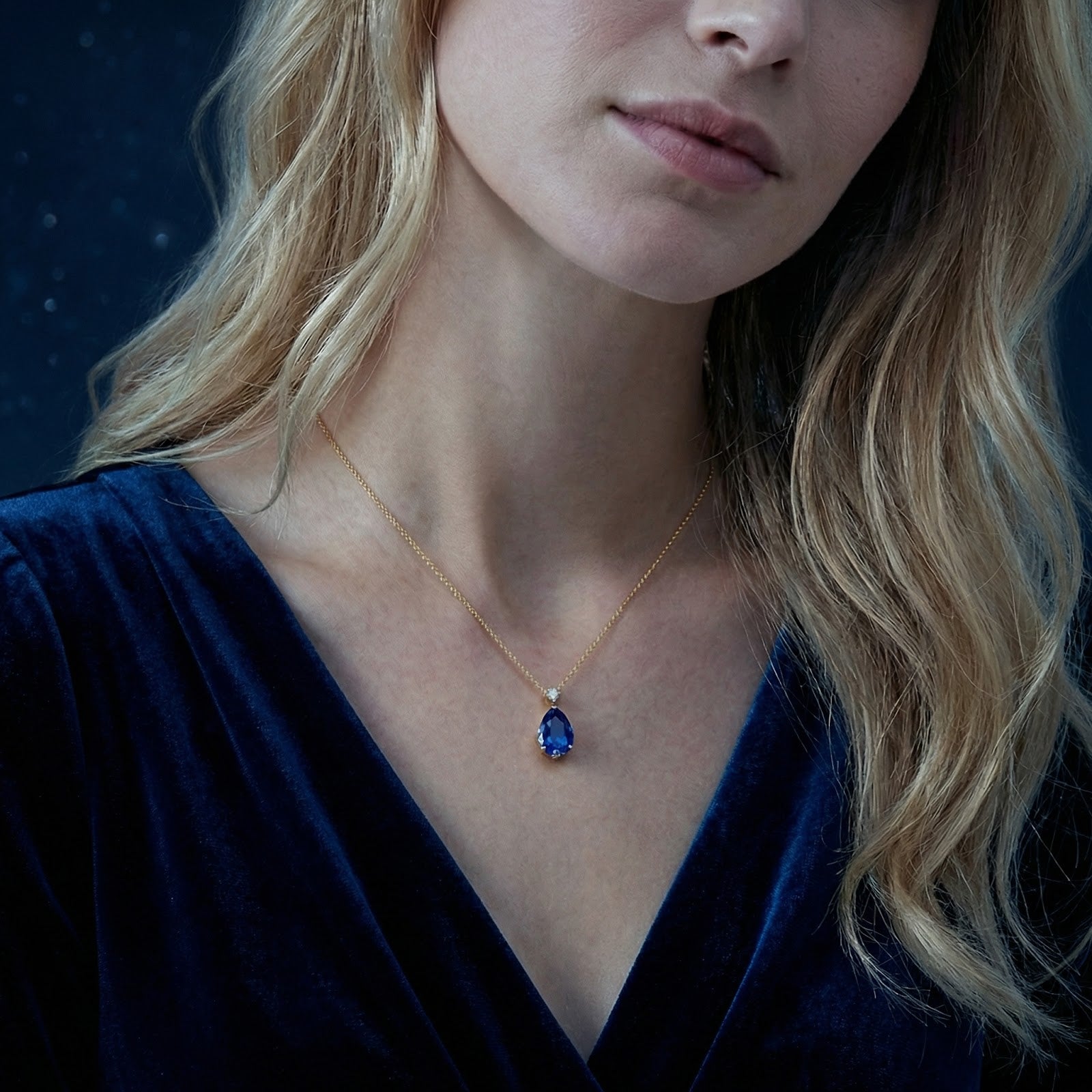 Model wearing a royal blue pear-cut simulated sapphire necklace in 18K gold vermeil.