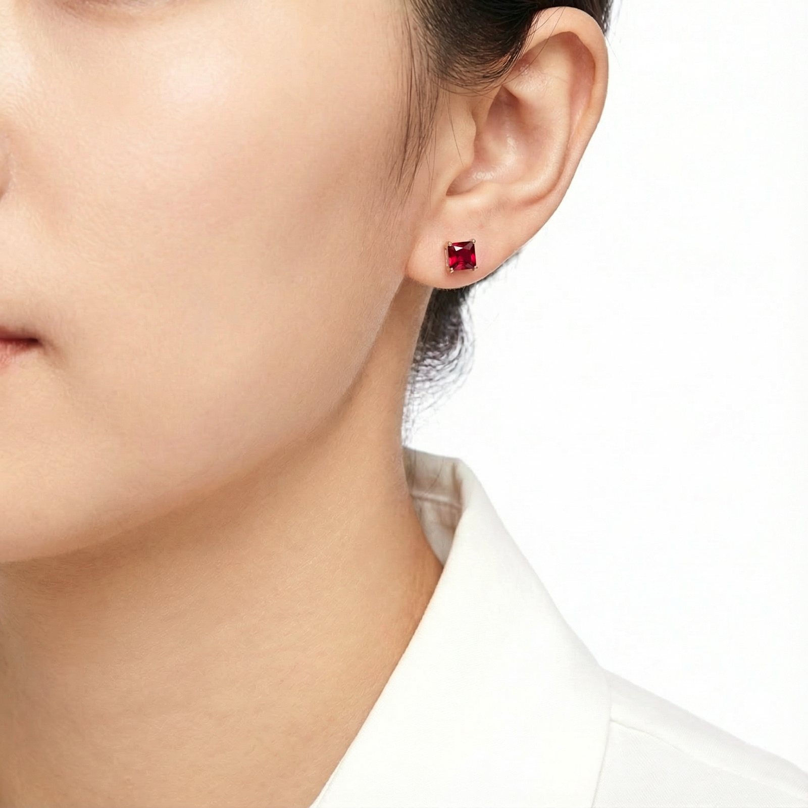 Woman wearing a square cut simulated ruby stud earring in 18K rose gold vermeil.