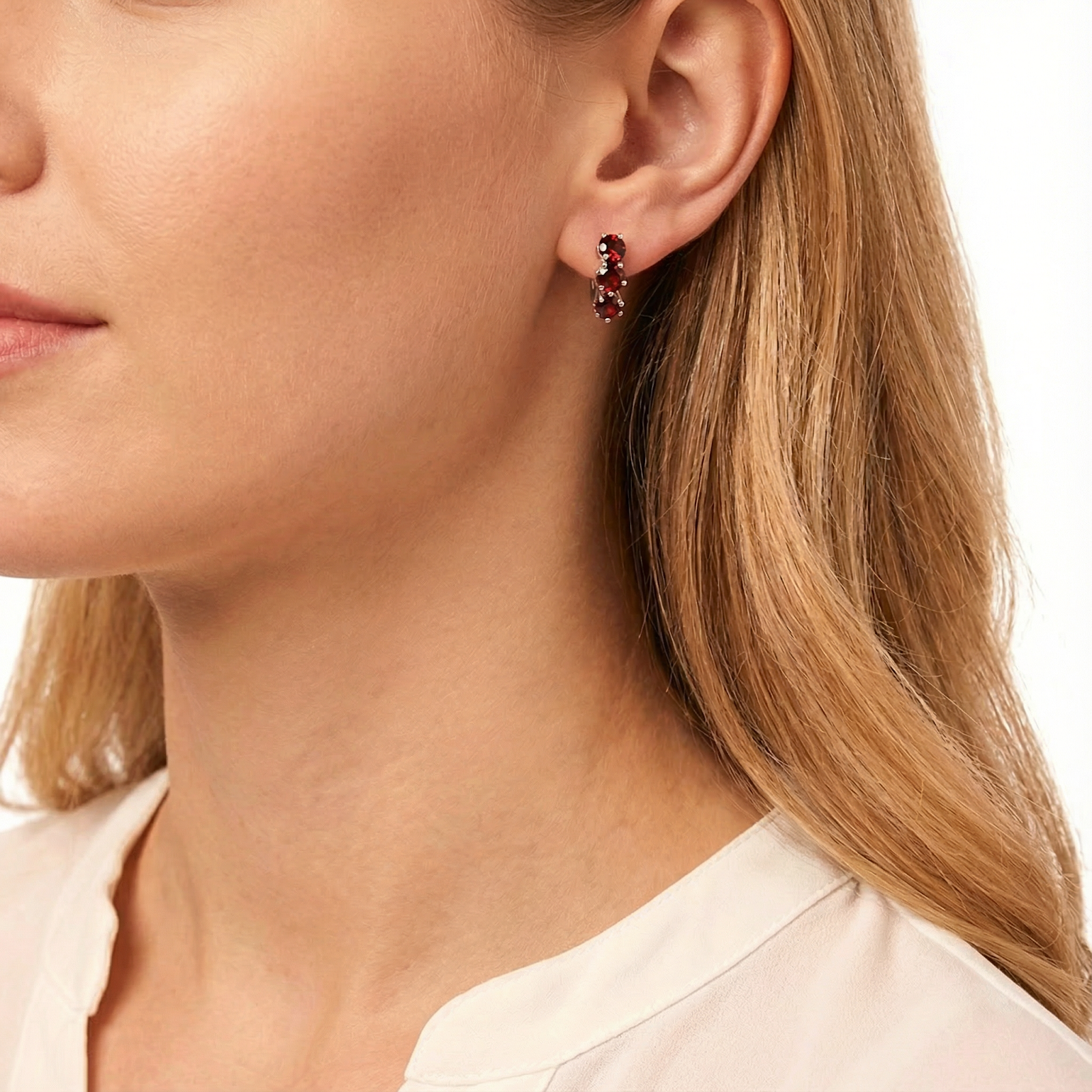 Profile view of a woman wearing S925 sterling silver huggie earrings with star-cut simulated garnets.