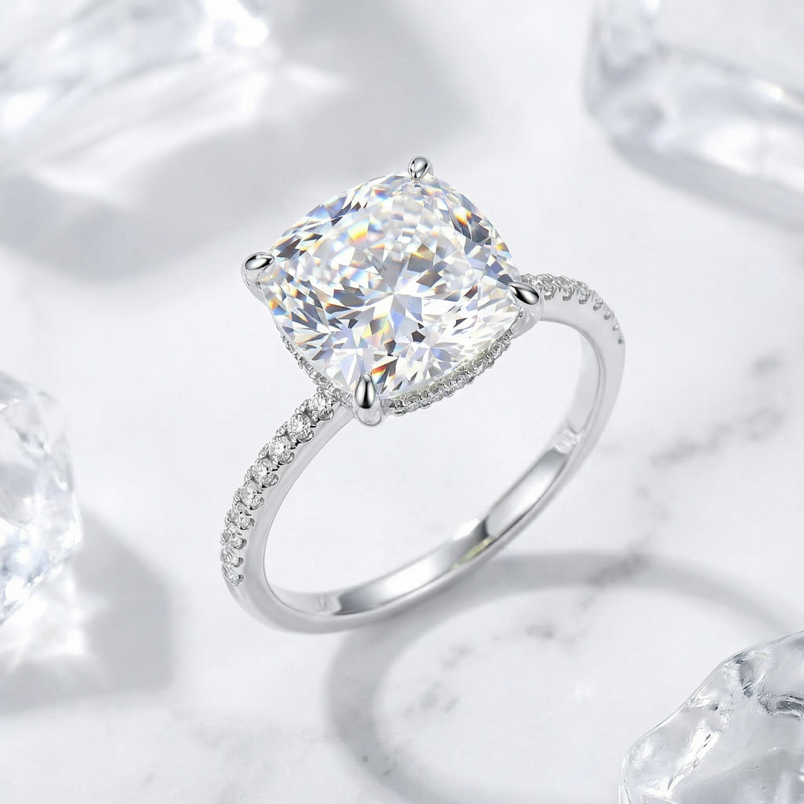 Cushion cut zirconia ring in S925 sterling silver with a pavé band, styled on marble with ice.