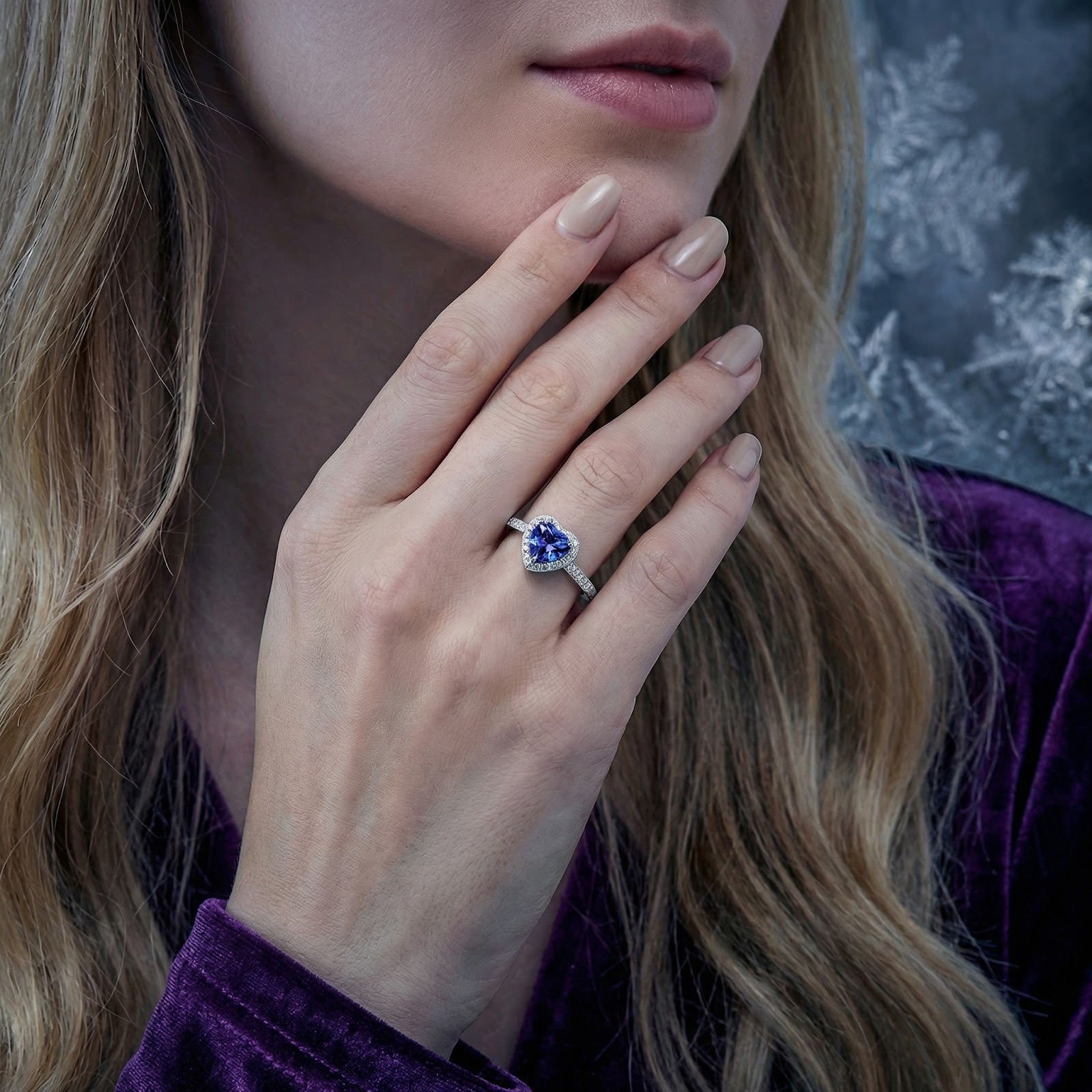 Woman wearing the heart-shaped simulated tanzanite sterling silver ring on her ring finger near her face.