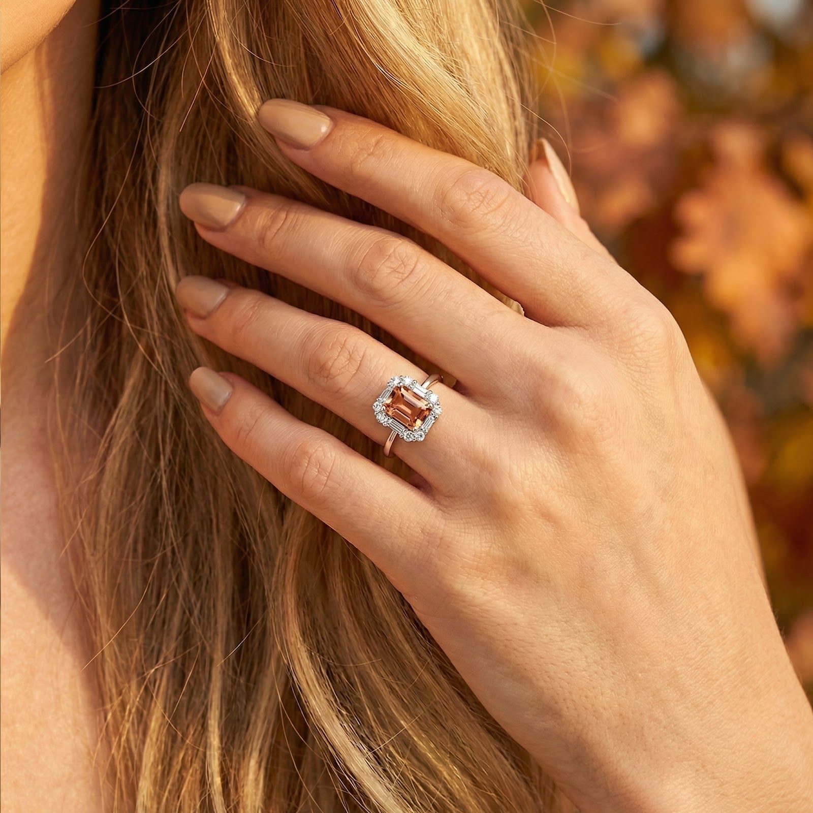 Close-up of a model's hand wearing the emerald-cut honey topaz ring in S925 sterling silver against fall foliage.