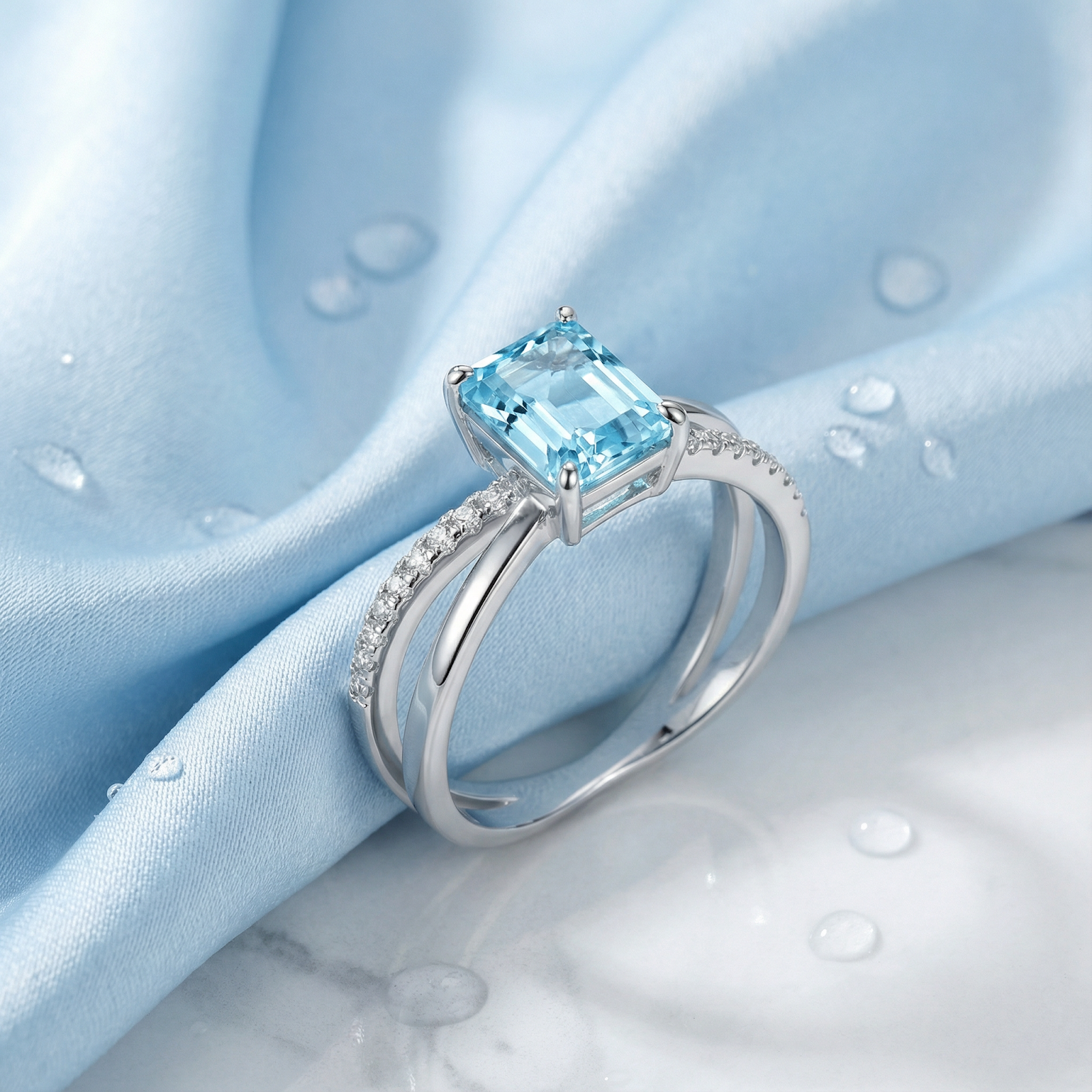Macro side view of an emerald cut simulated aquamarine ring in S925 sterling silver on blue silk.