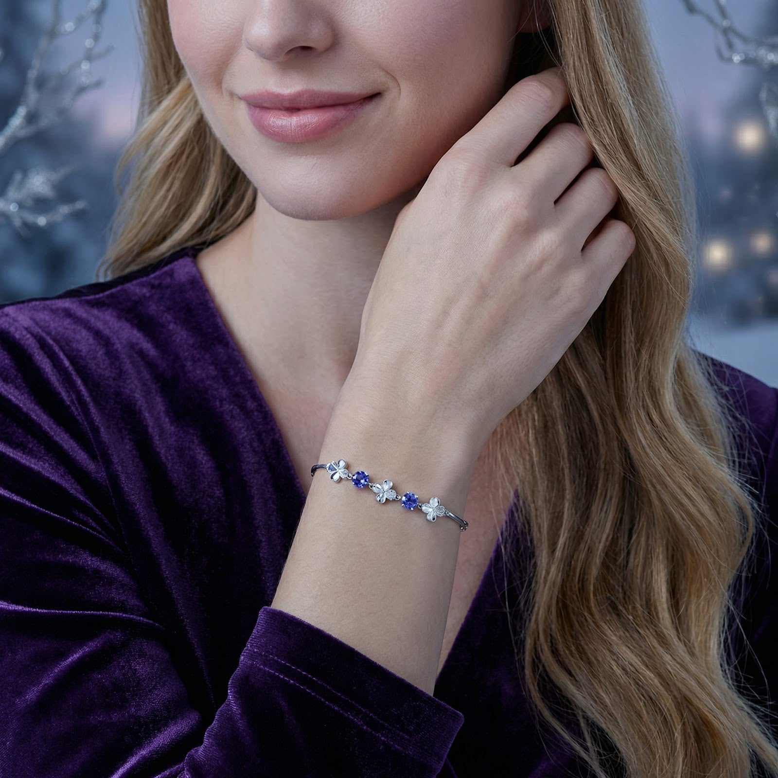 Model wearing the silver Olyraea clover bracelet with blue simulated tanzanite stones on her wrist.