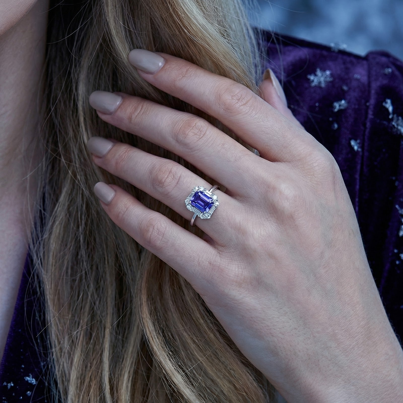 Close-up of the emerald cut simulated tanzanite sterling silver ring worn on a model's hand.
