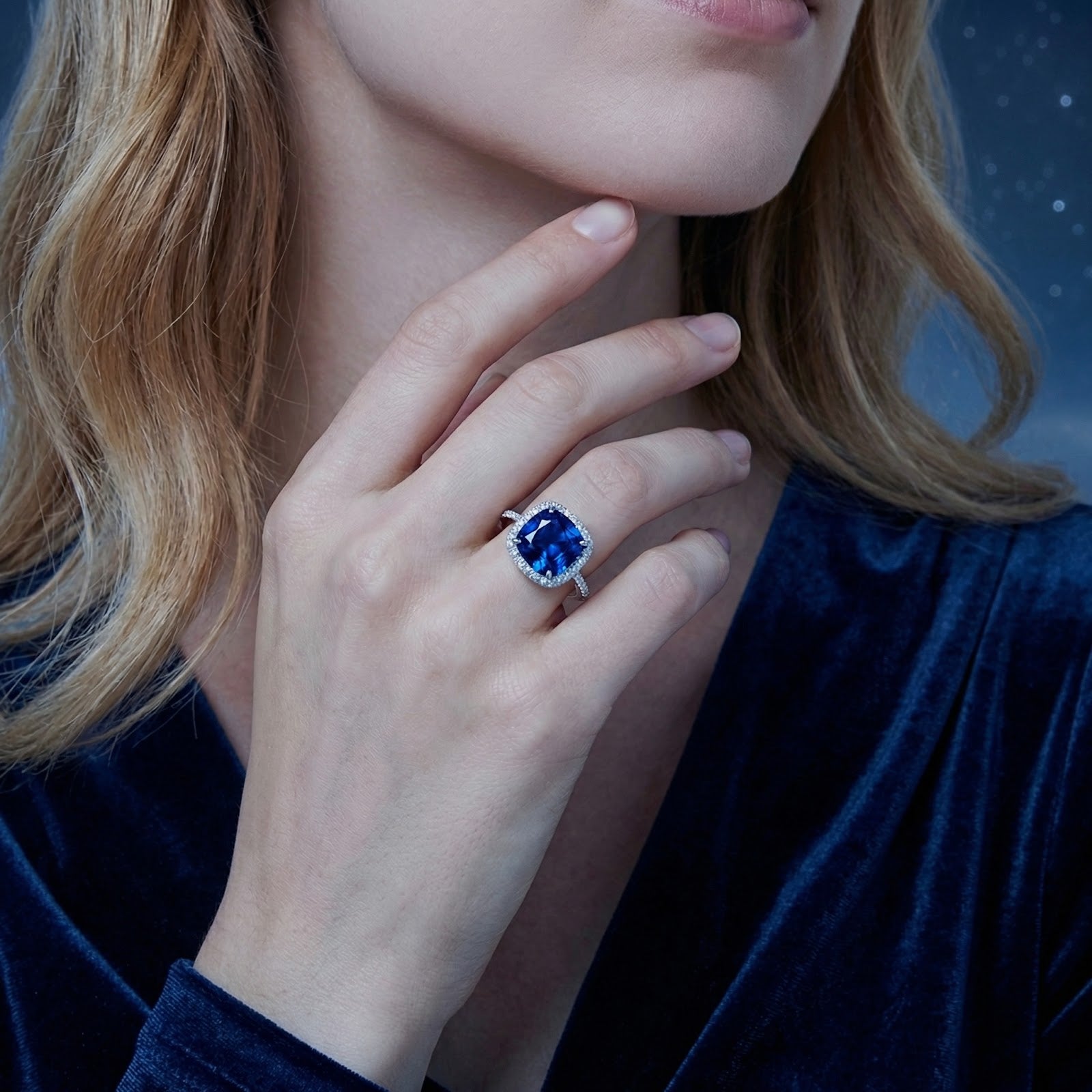 Model wearing the cushion-cut blue sapphire halo ring in S925 sterling silver against a dark background.