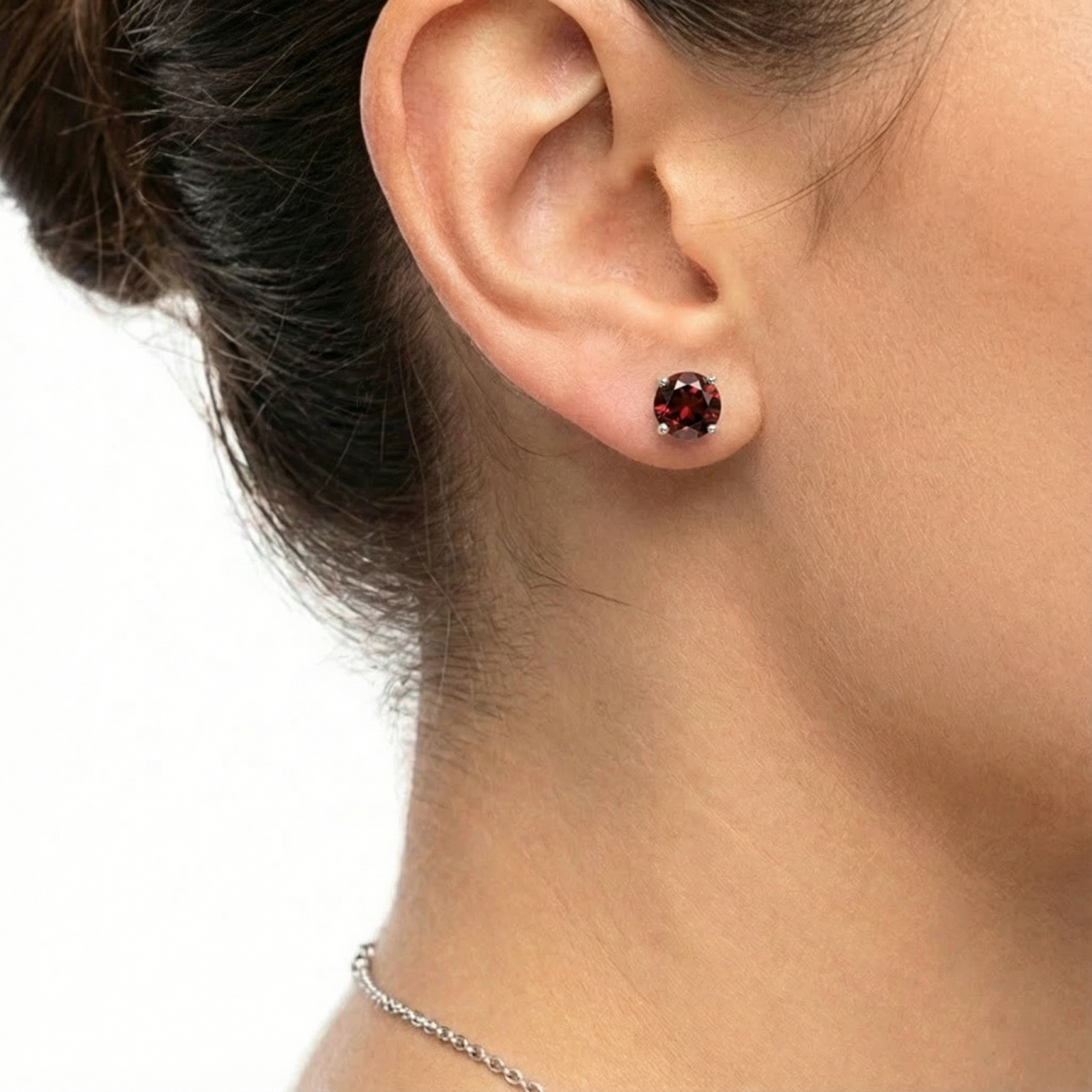 Round cut simulated garnet stud earring in S925 sterling silver worn on a woman's ear.