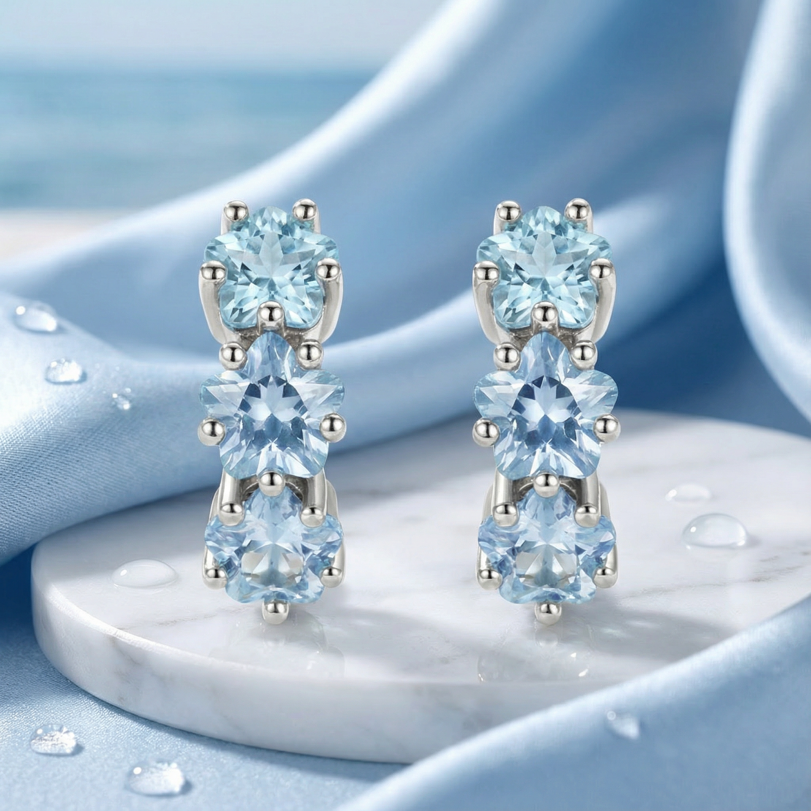 Macro view of sterling silver Astra Star Hoops showing the detail of three star-cut light blue aquamarine stones.