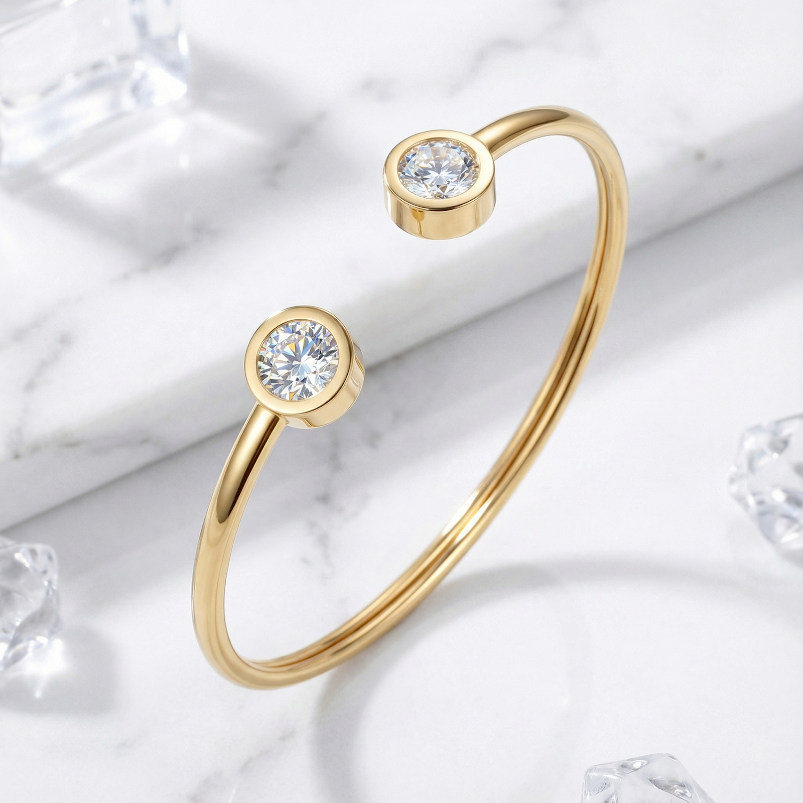 Gold stainless steel cuff bracelet with round-cut simulated diamonds on a marble surface with ice cubes.