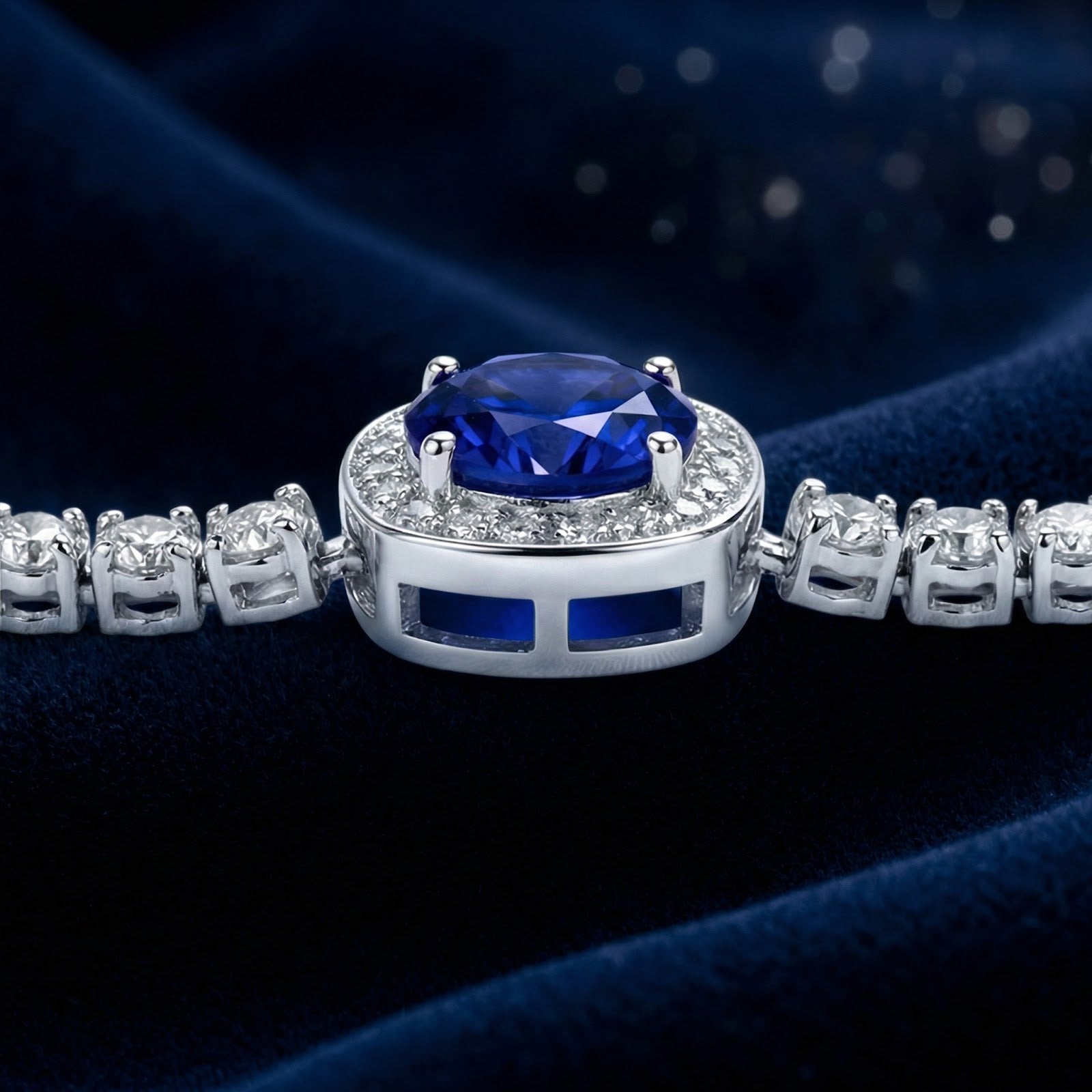 Macro view of a round simulated sapphire in a sterling silver halo setting on blue velvet.