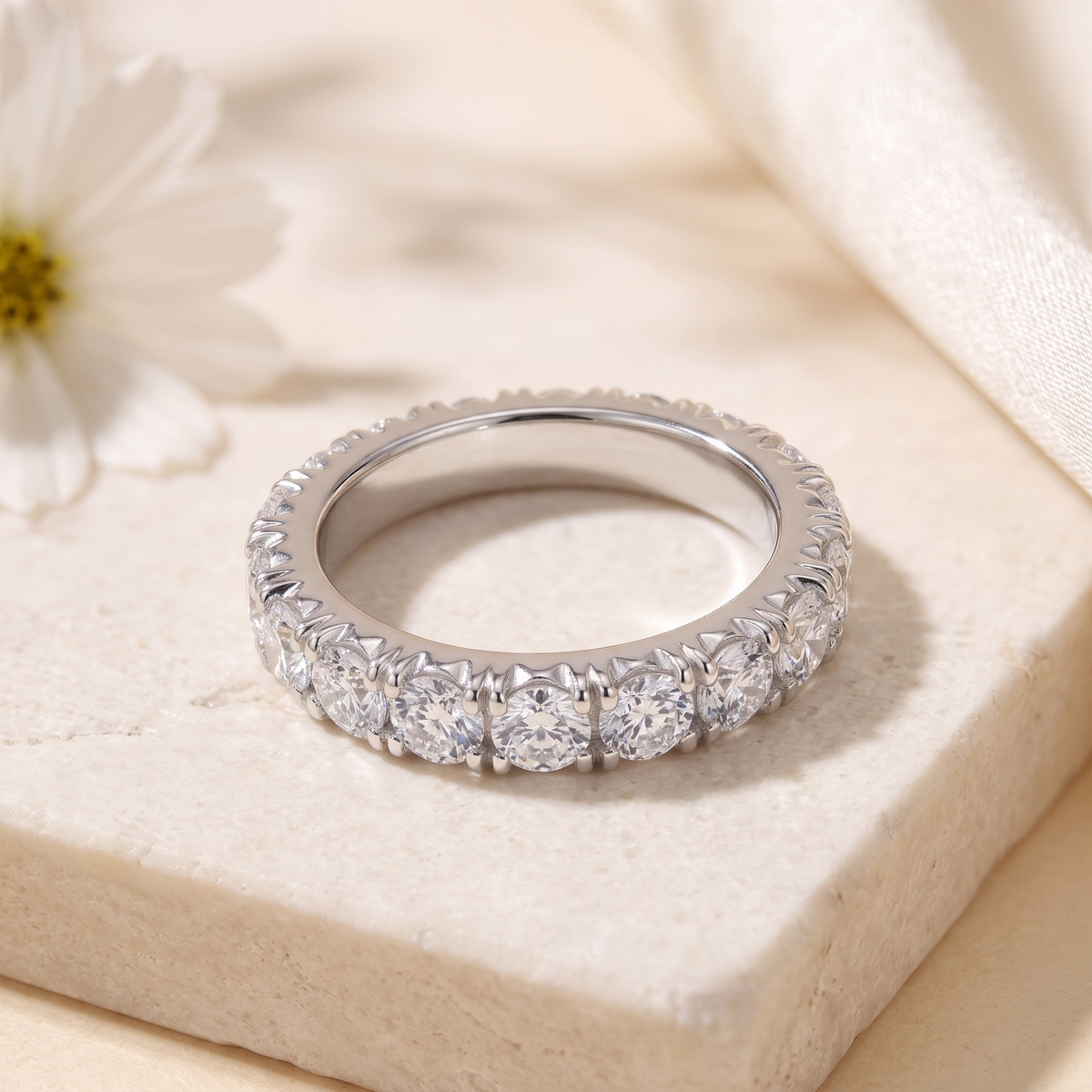 Round moissanite eternity band in silver, angled closeup.
