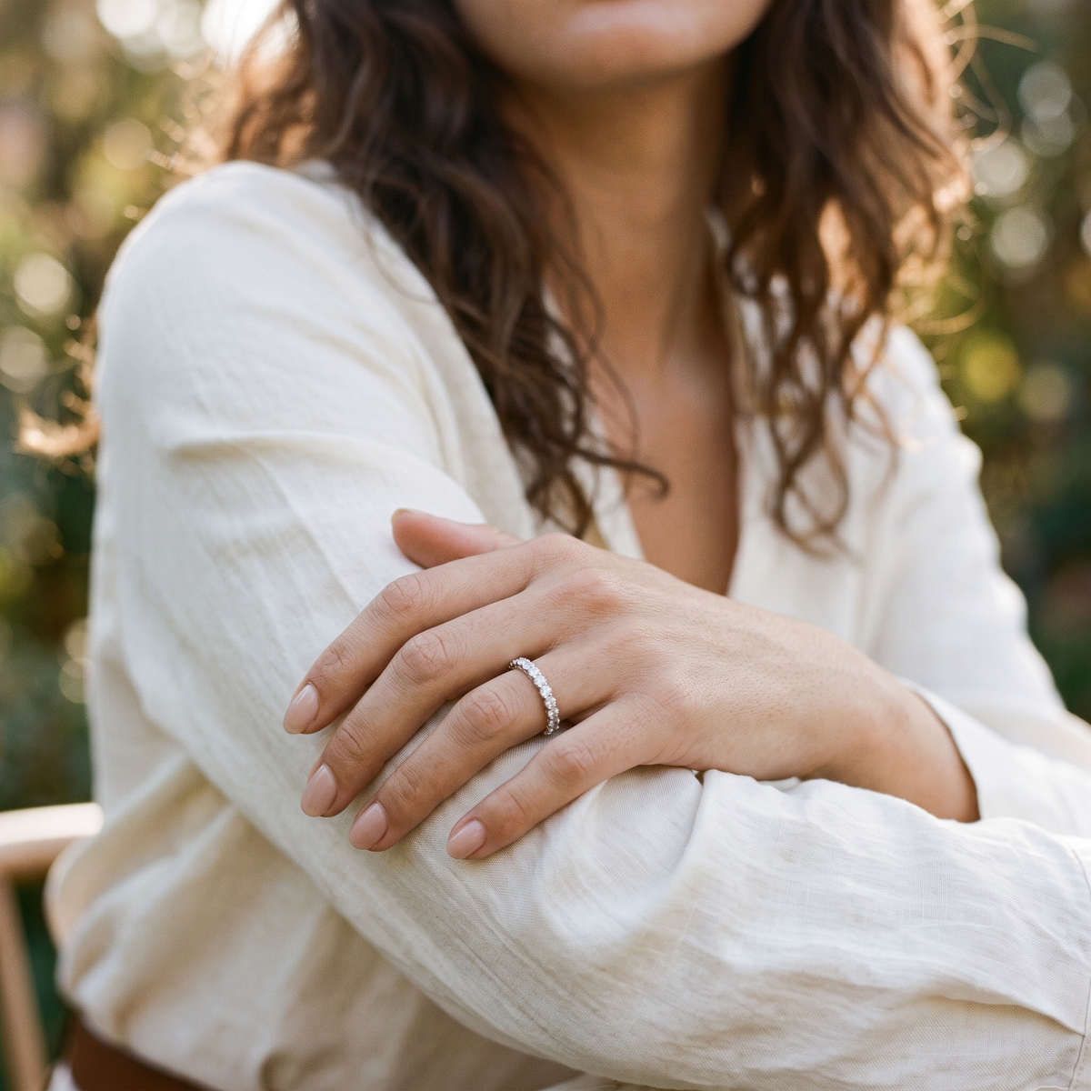 Silver moissanite eternity band worn on a model's hand resting on her forearm.
