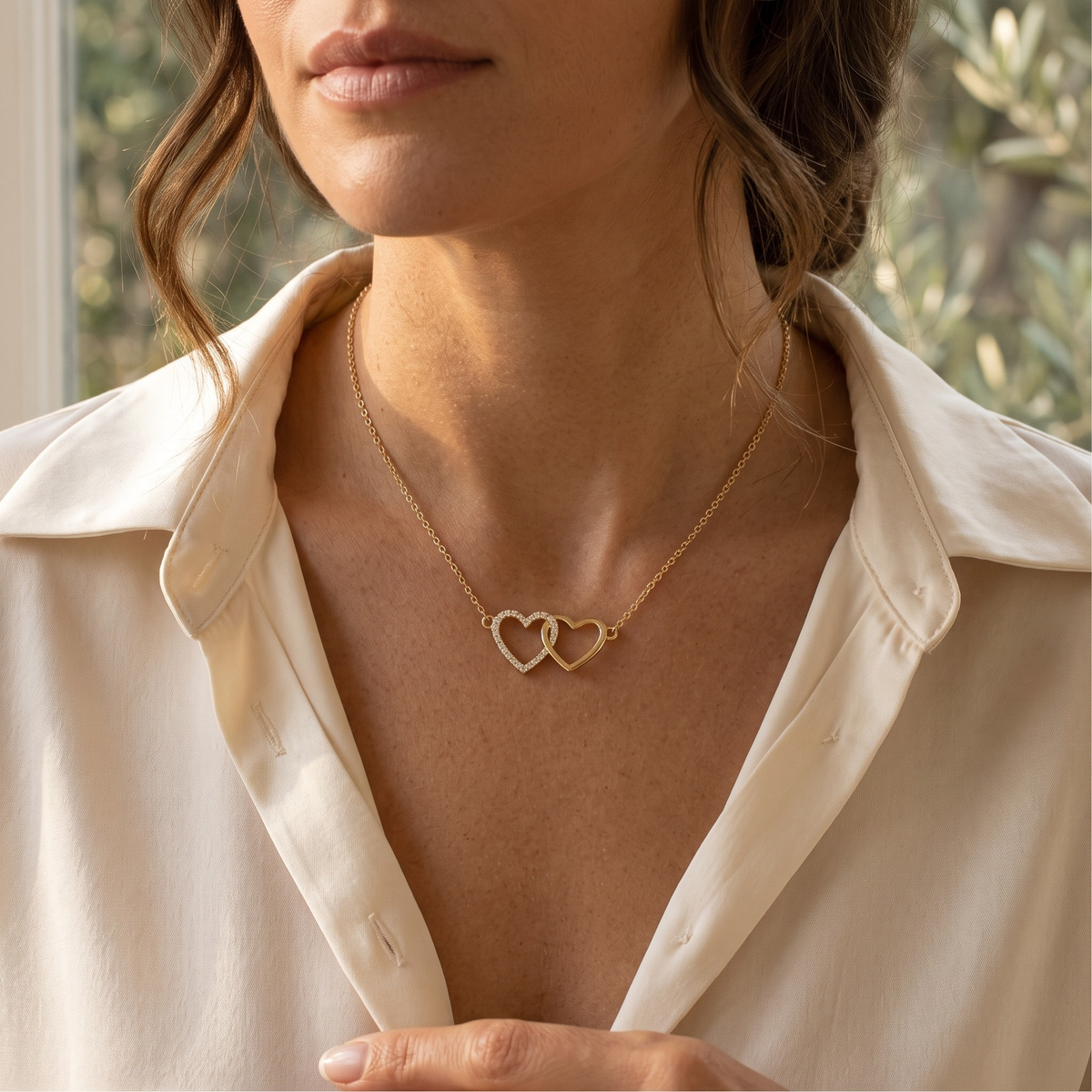 Interlocking heart necklace in yellow gold, worn at a model's neckline
