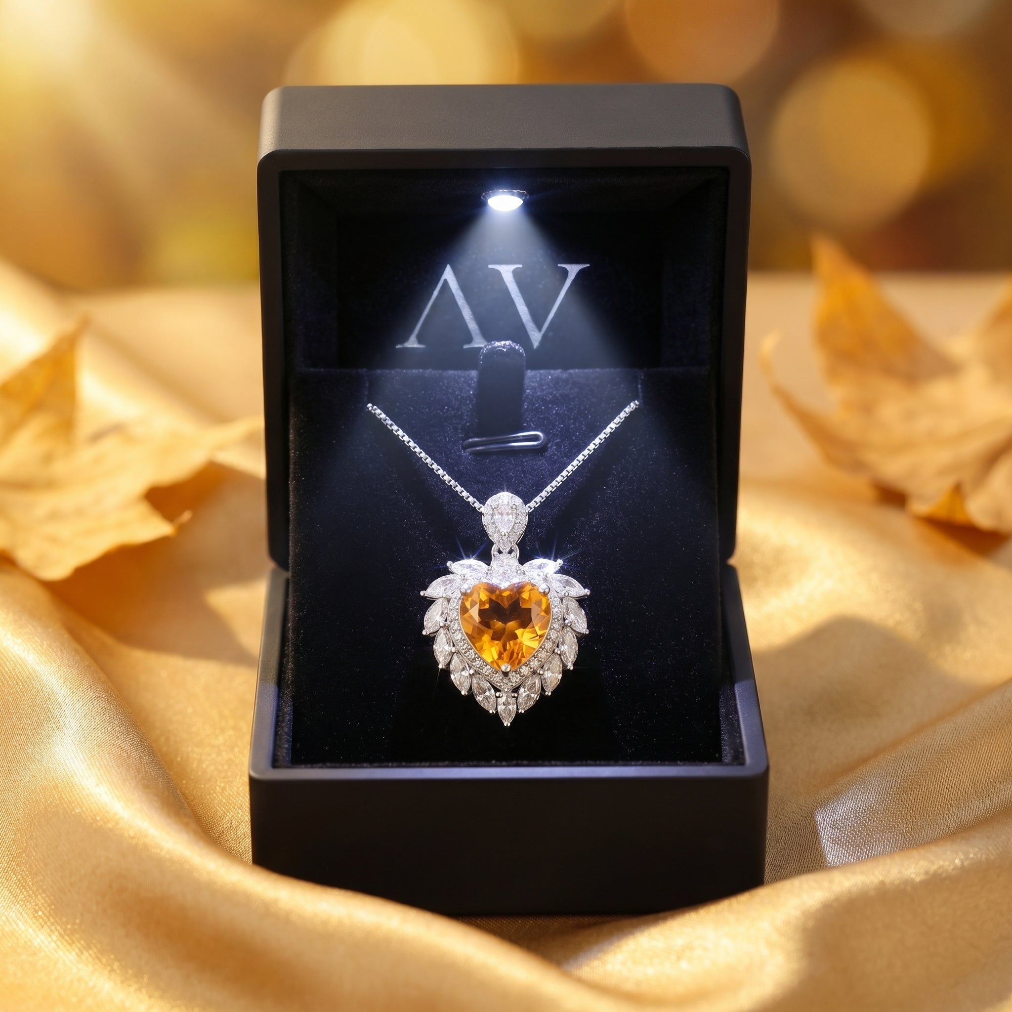 Heart cut citrine necklace in a silver setting inside a black LED-lit gift box on golden fabric.