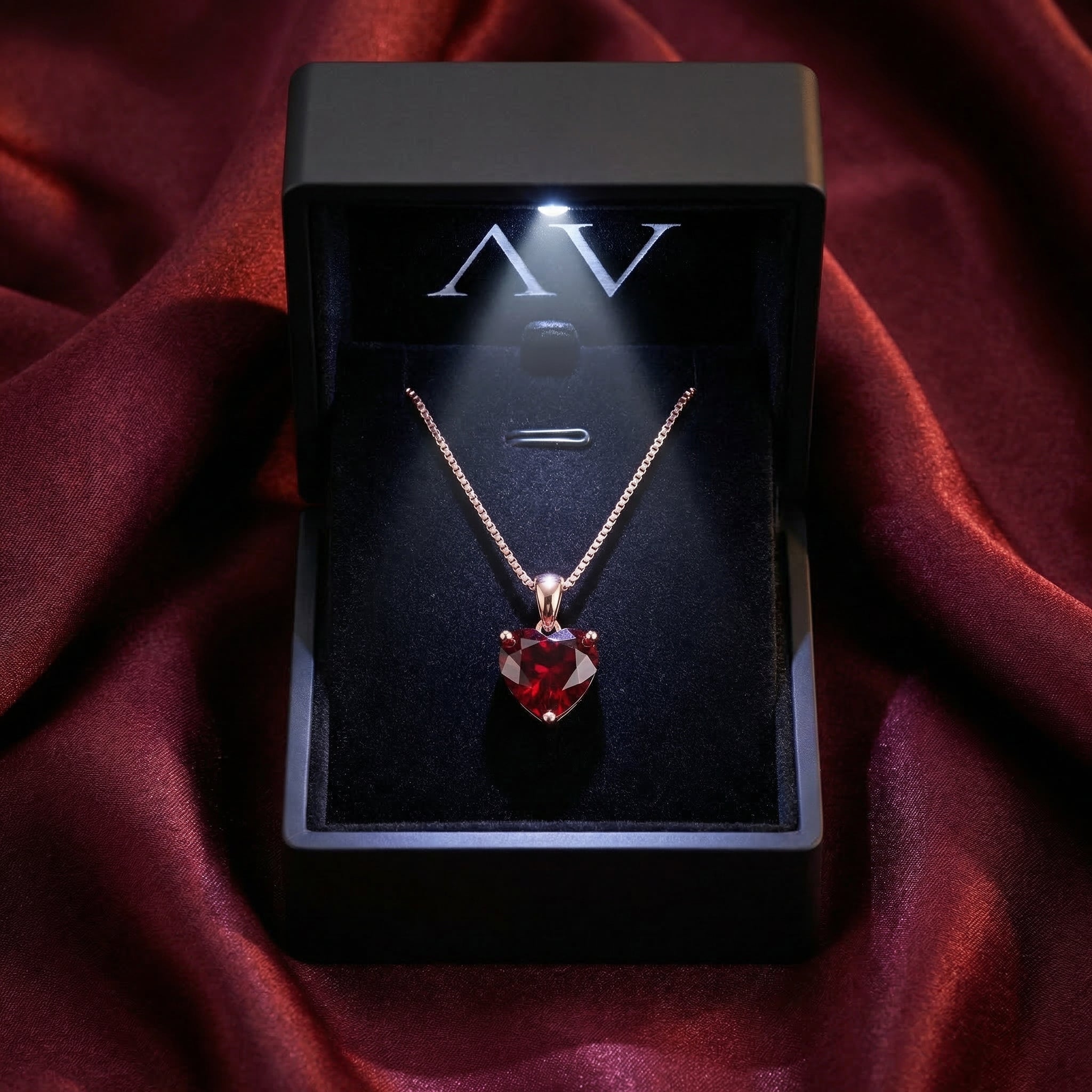 Heart cut garnet necklace in 18K rose gold inside a black illuminated jewelry box.