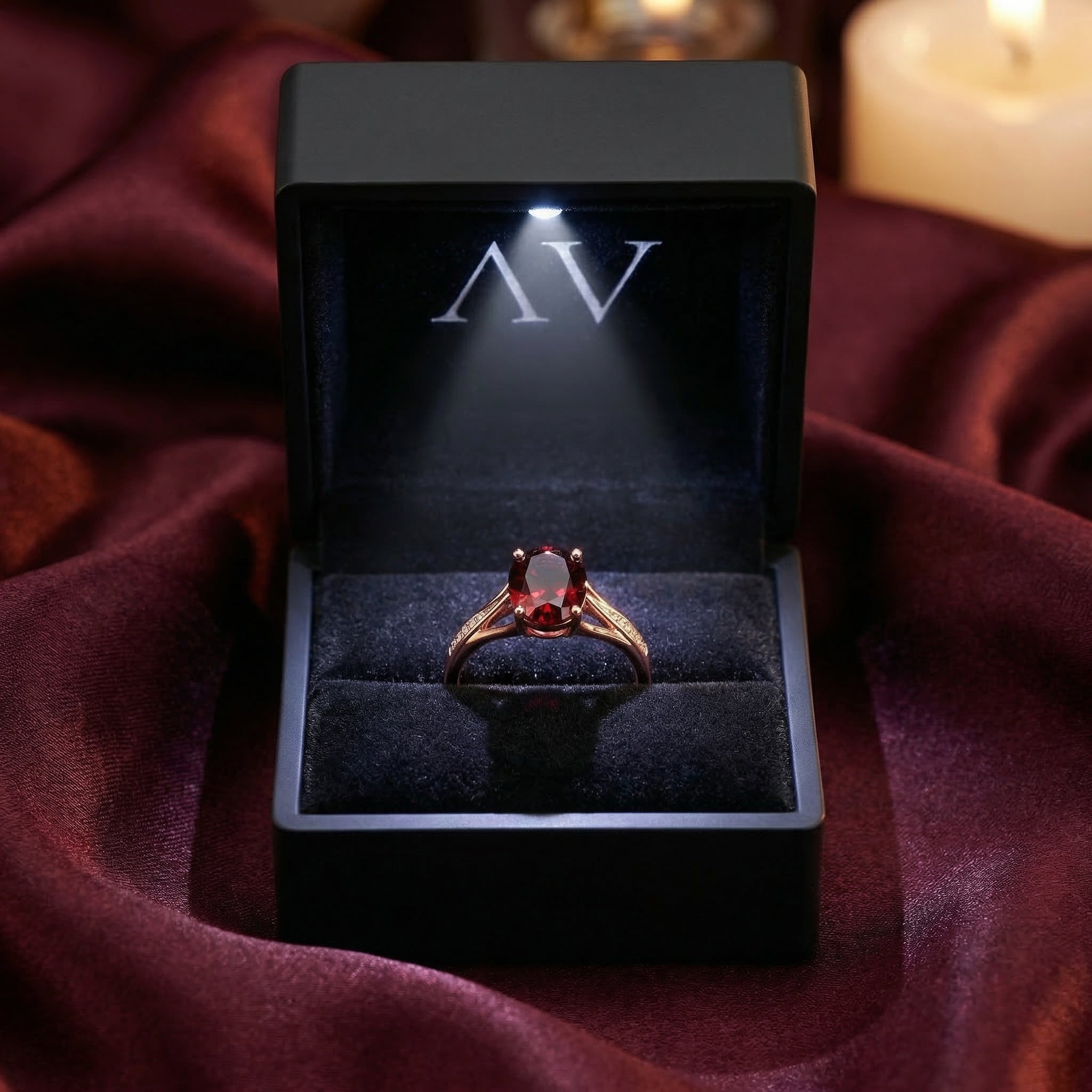 Oval natural garnet ring in 18K rose gold presented in a premium black LED-lit jewelry gift box on red silk.