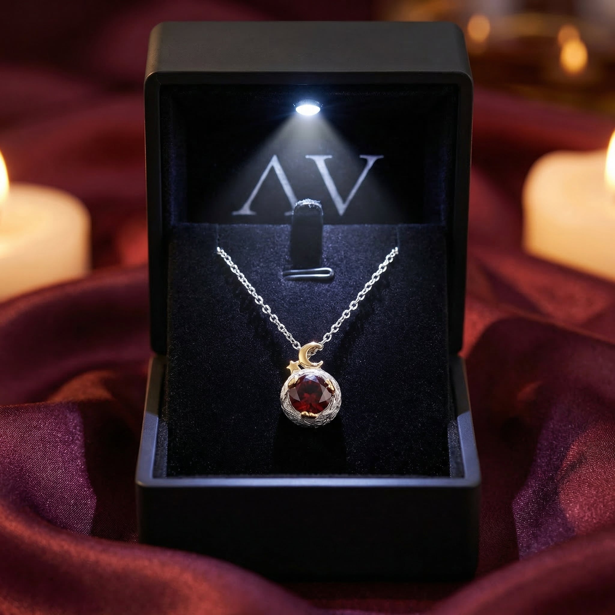 The Ember round garnet necklace in a black lighted presentation box, showcasing the round cut gemstone.