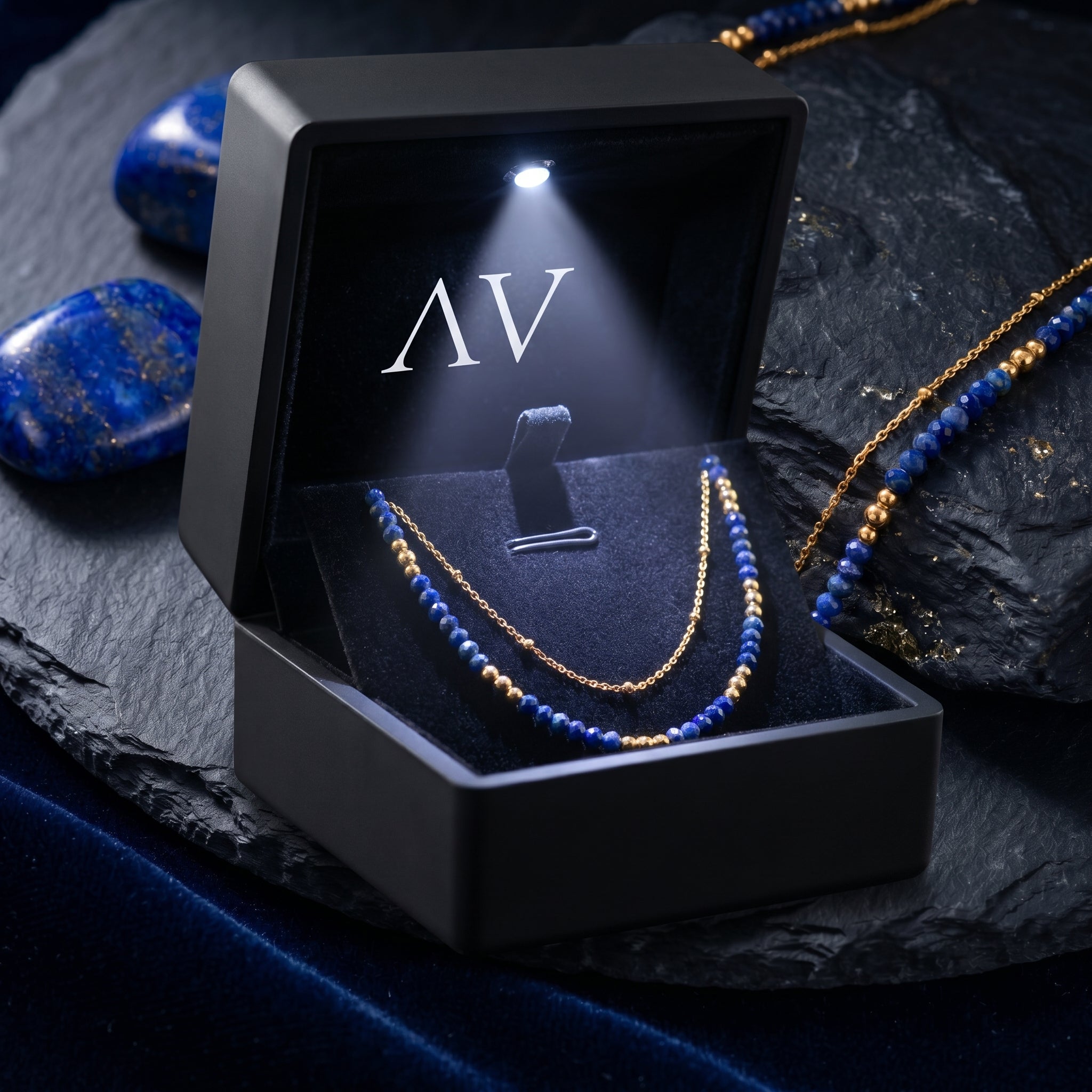 Gold and lapis lazuli layered necklace presented in a black light-up jewelry box with the AV logo.