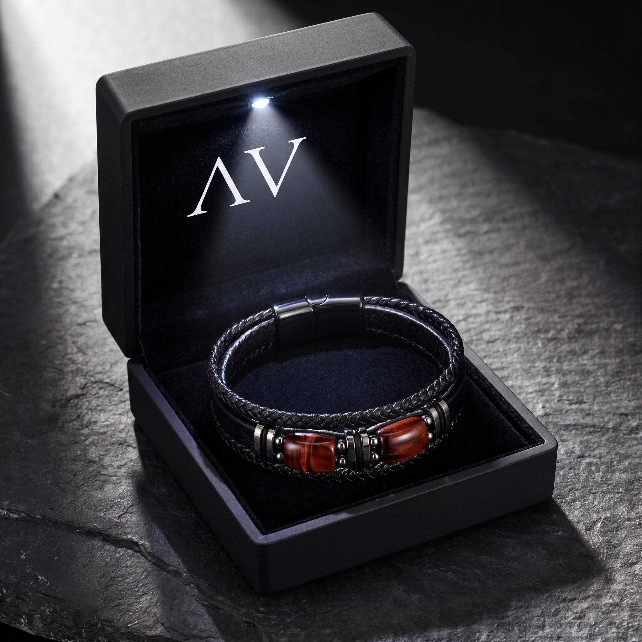 Black braided leather bracelet with red-toned accents inside a premium black LED-lit gift box with AV logo.