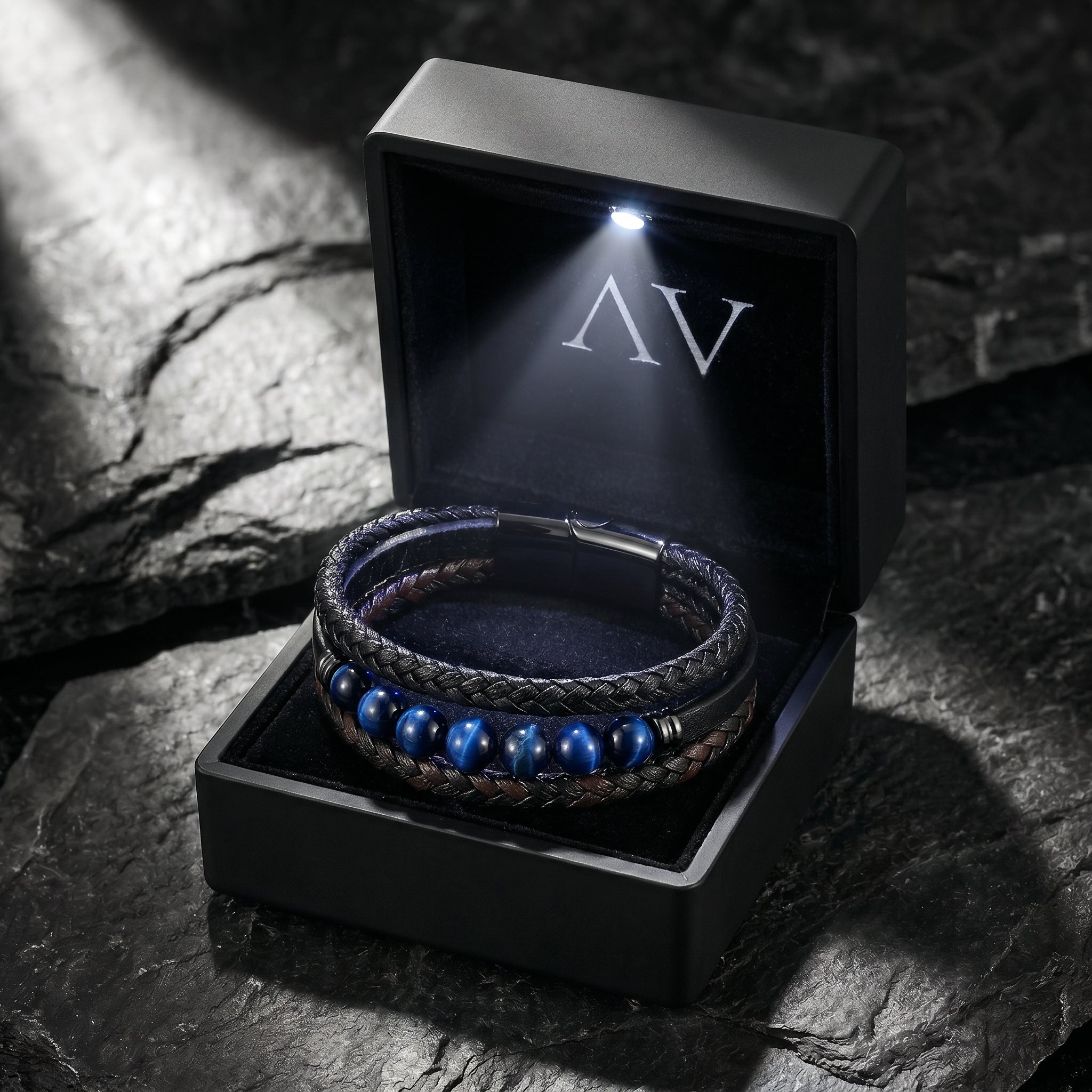 The Eclipse leather bracelet with blue beads inside a premium black LED-lit gift box on a dark stone surface.