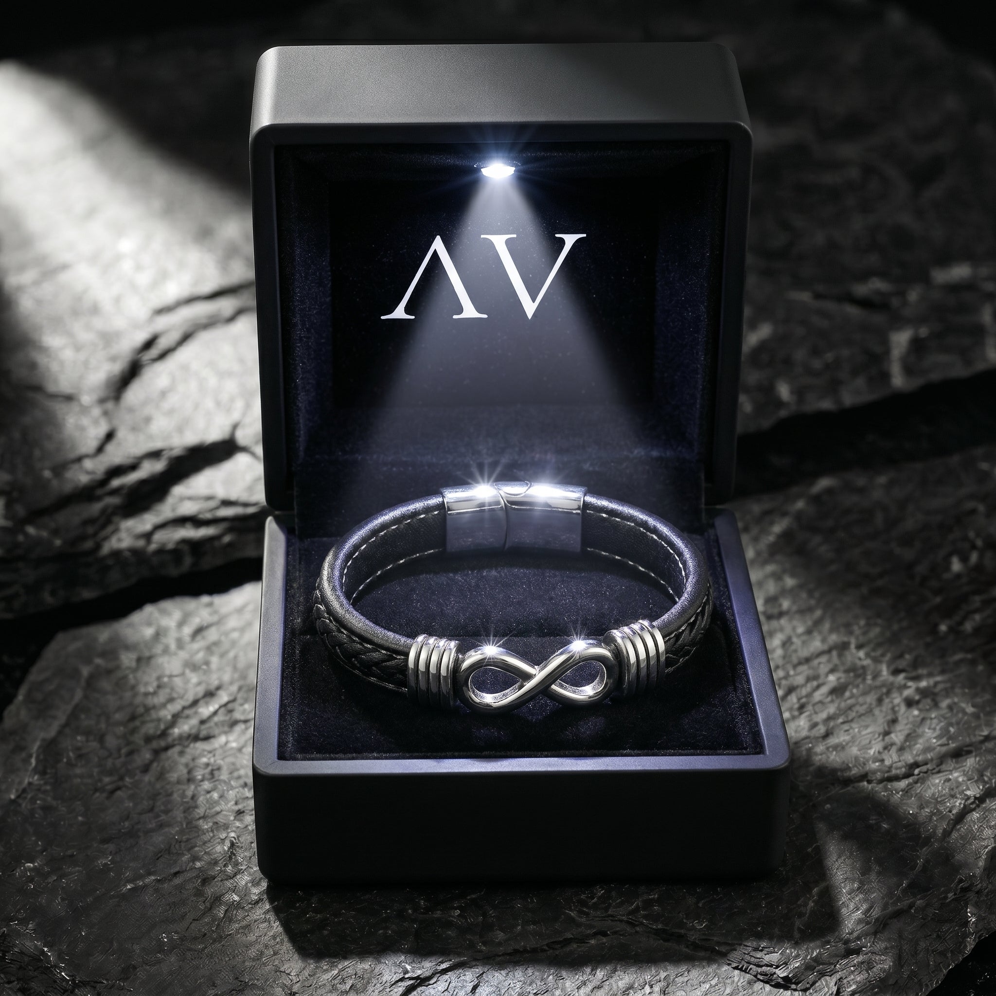 Men's black braided leather bracelet with a silver stainless steel infinity clasp in a lighted black gift box.