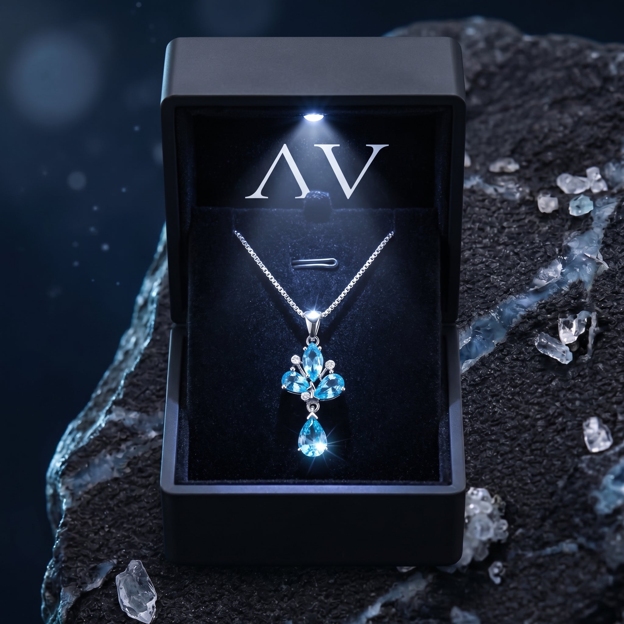 Zephyrine blue topaz necklace presented in a luxury black LED-lit gift box on a textured surface.