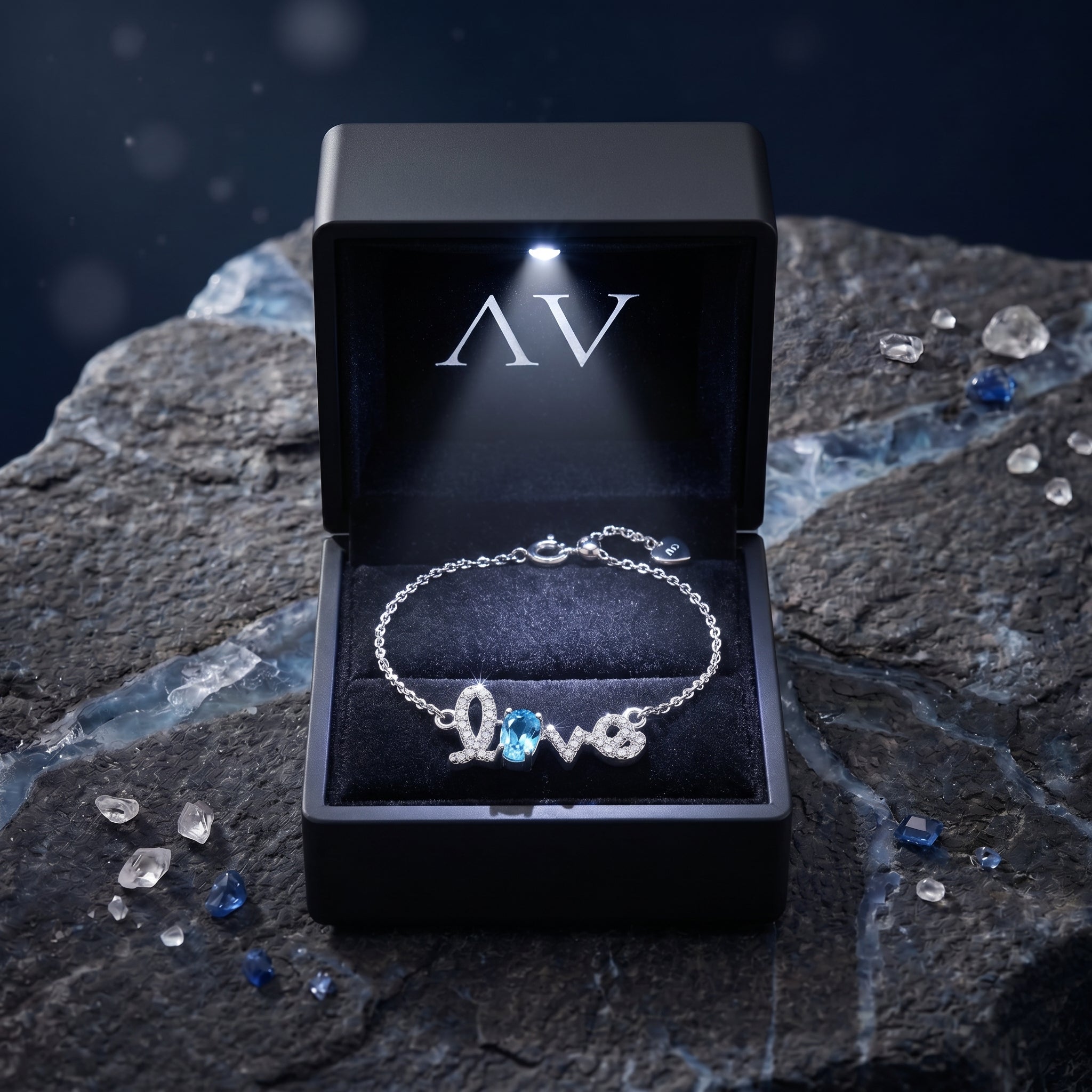 Silver Swiss Blue Topaz Love bracelet inside a luxury black lighted jewelry box on a rock background.