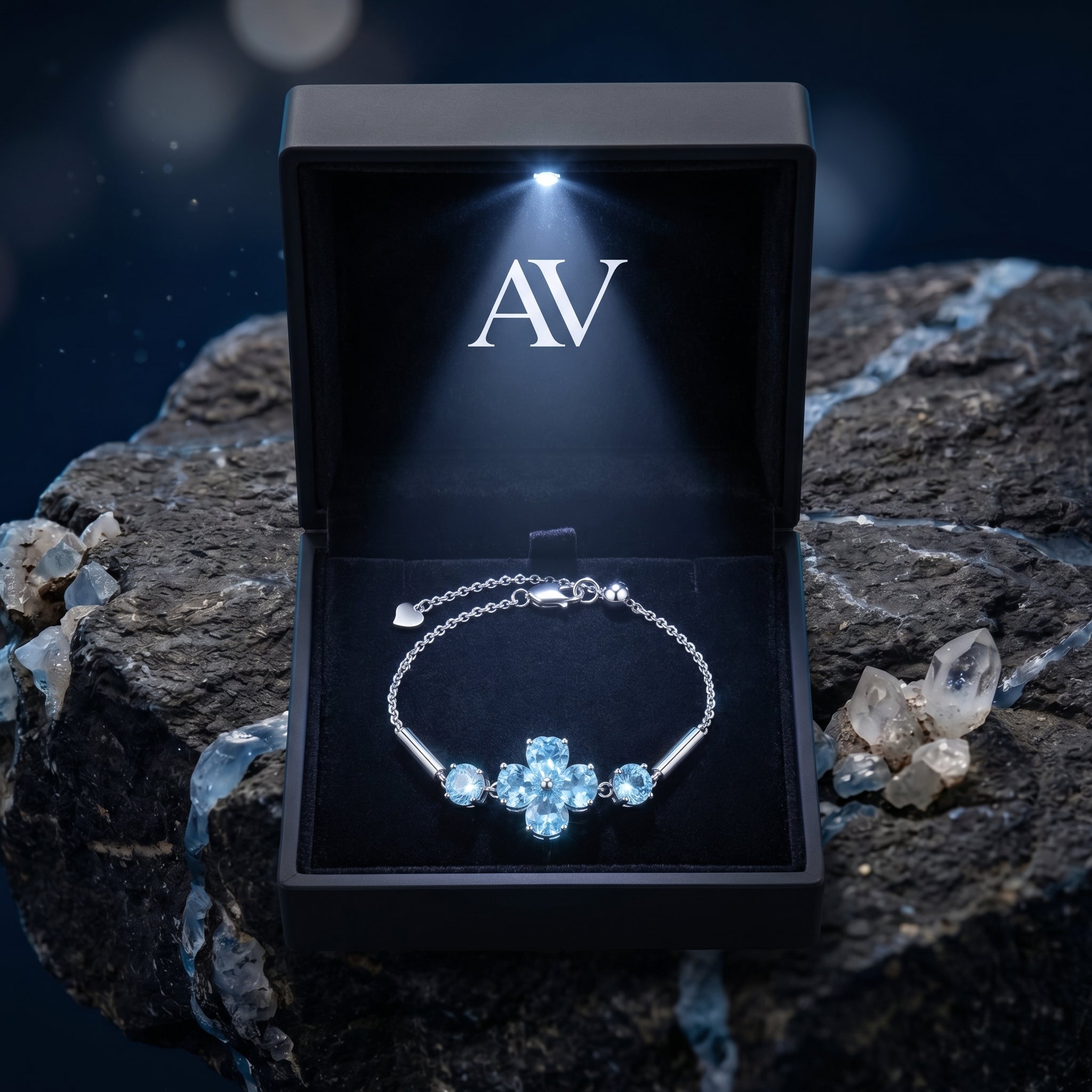 Silver Swiss blue topaz clover bracelet with heart and round cuts in a lighted black AV branded gift box.