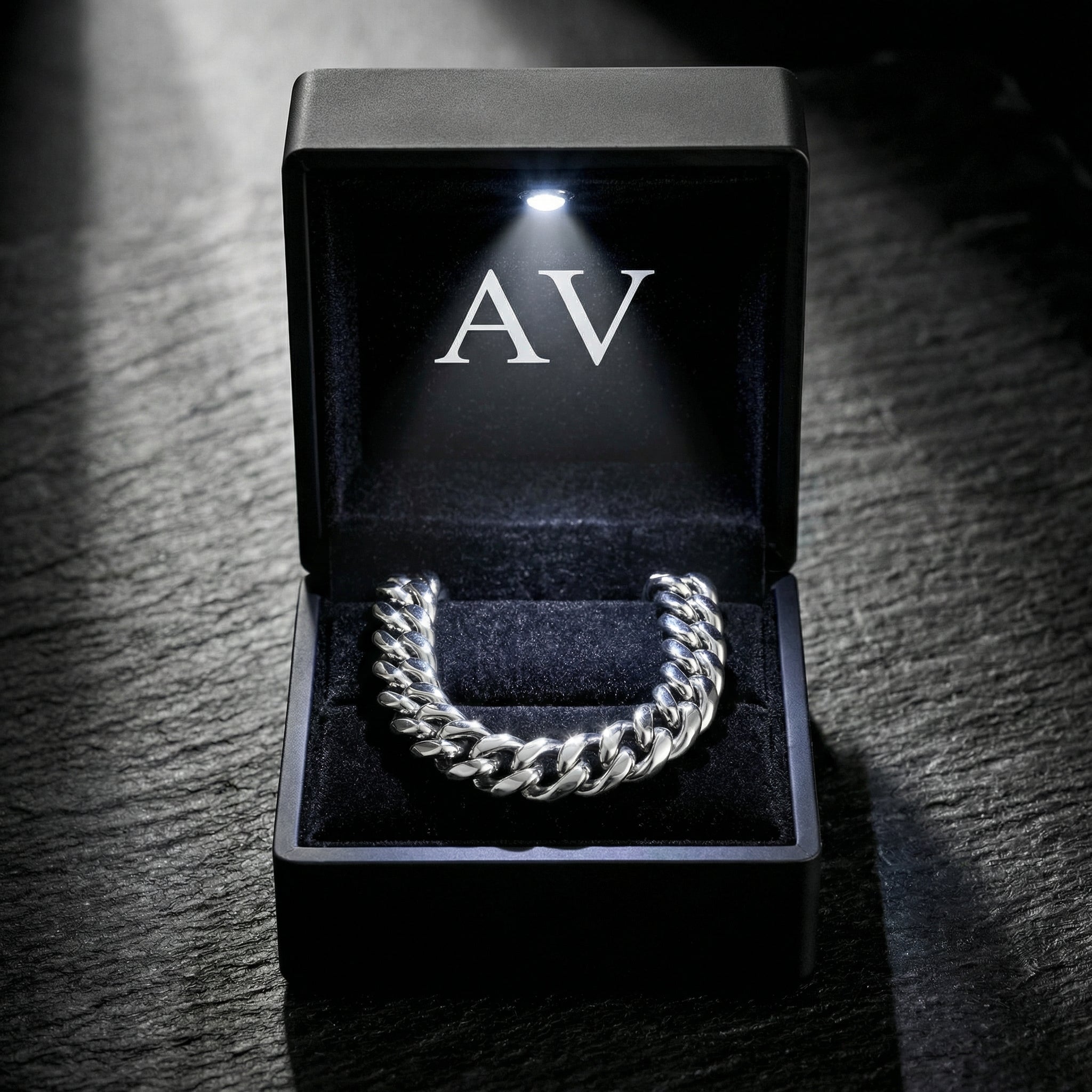 Silver stainless steel Cuban link bracelet inside a black LED-lit gift box with AV branding.