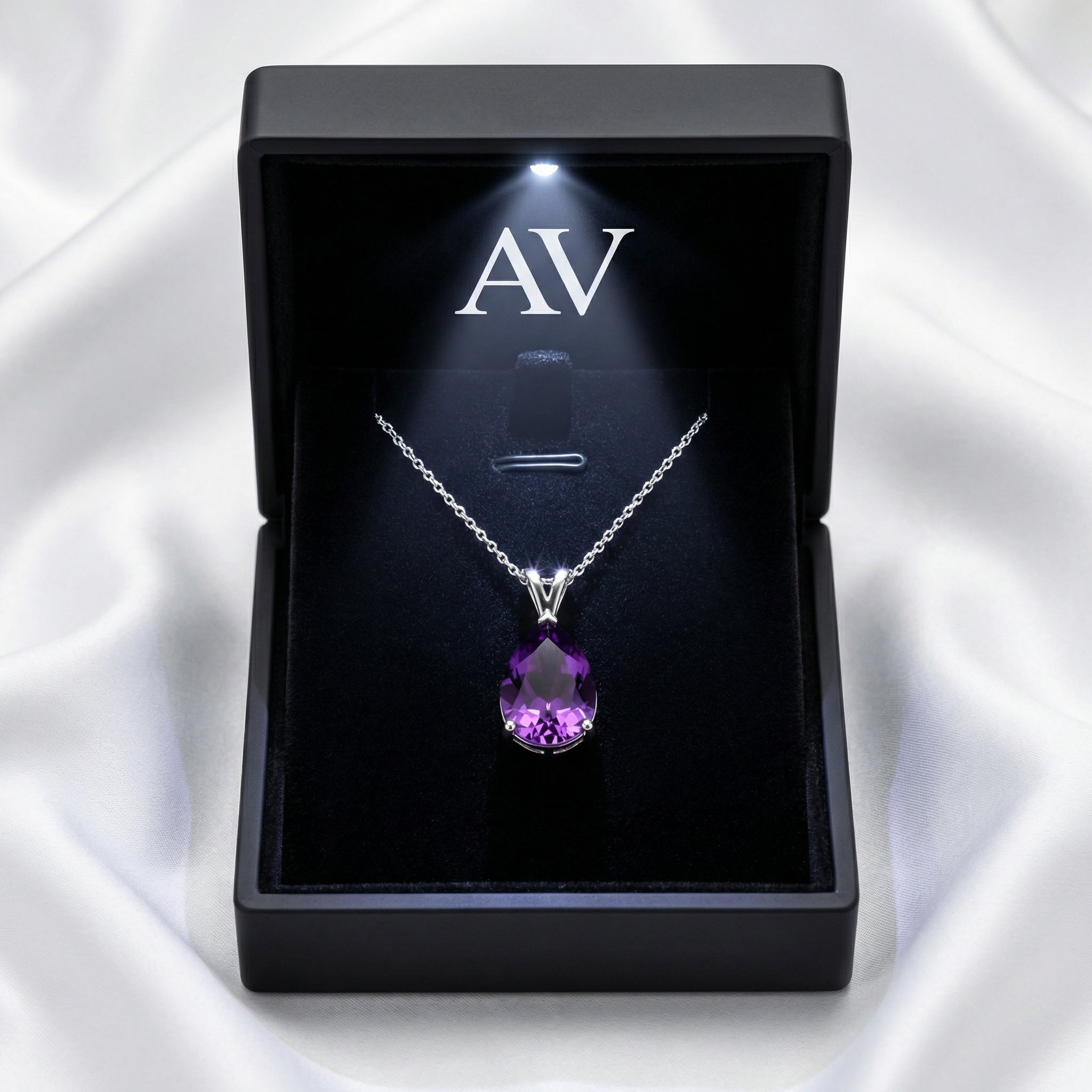 Purple moissanite teardrop necklace presented in a black LED-lit jewelry gift box on white silk.