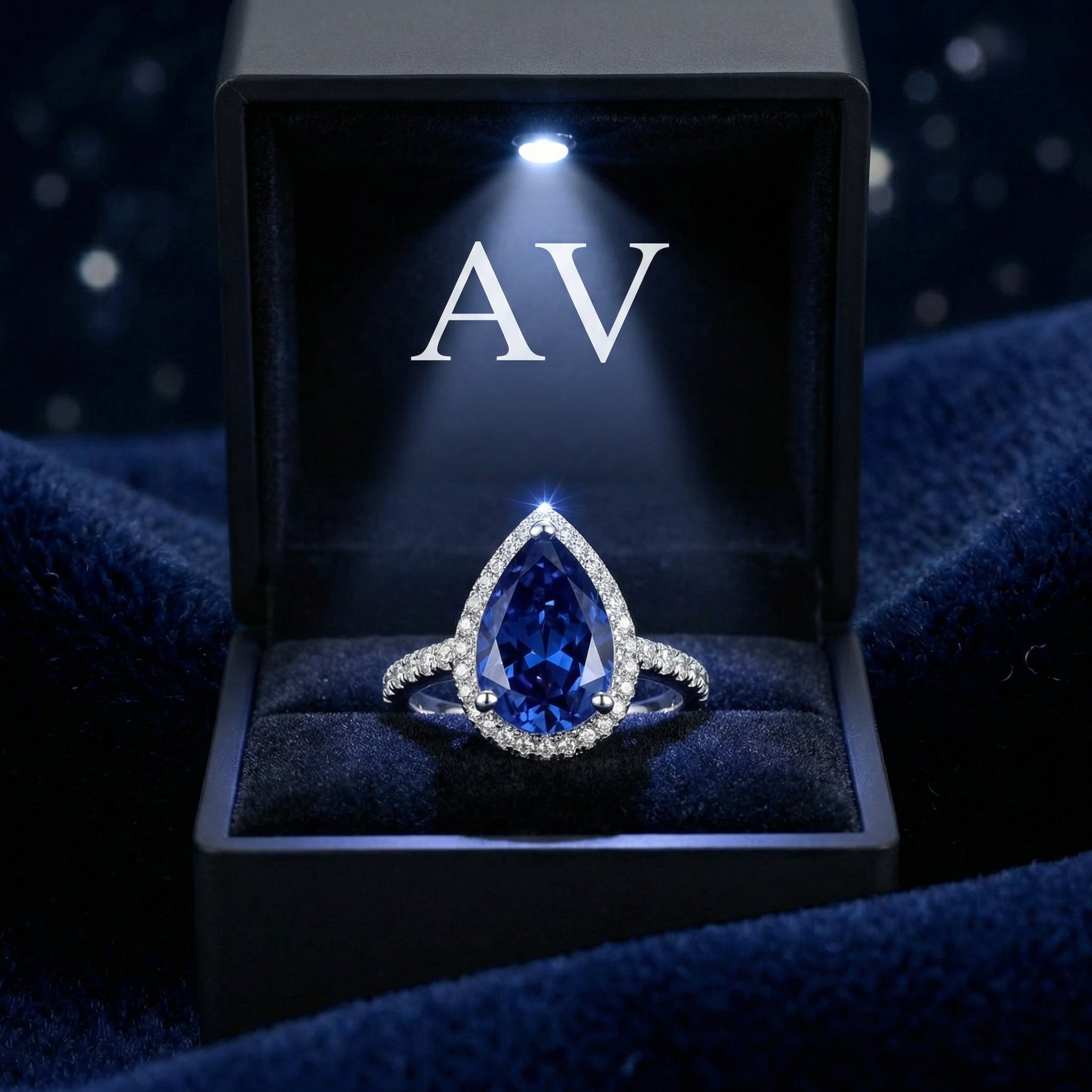 Pear cut simulated sapphire sterling silver ring inside a lighted black jewelry box with AV logo.