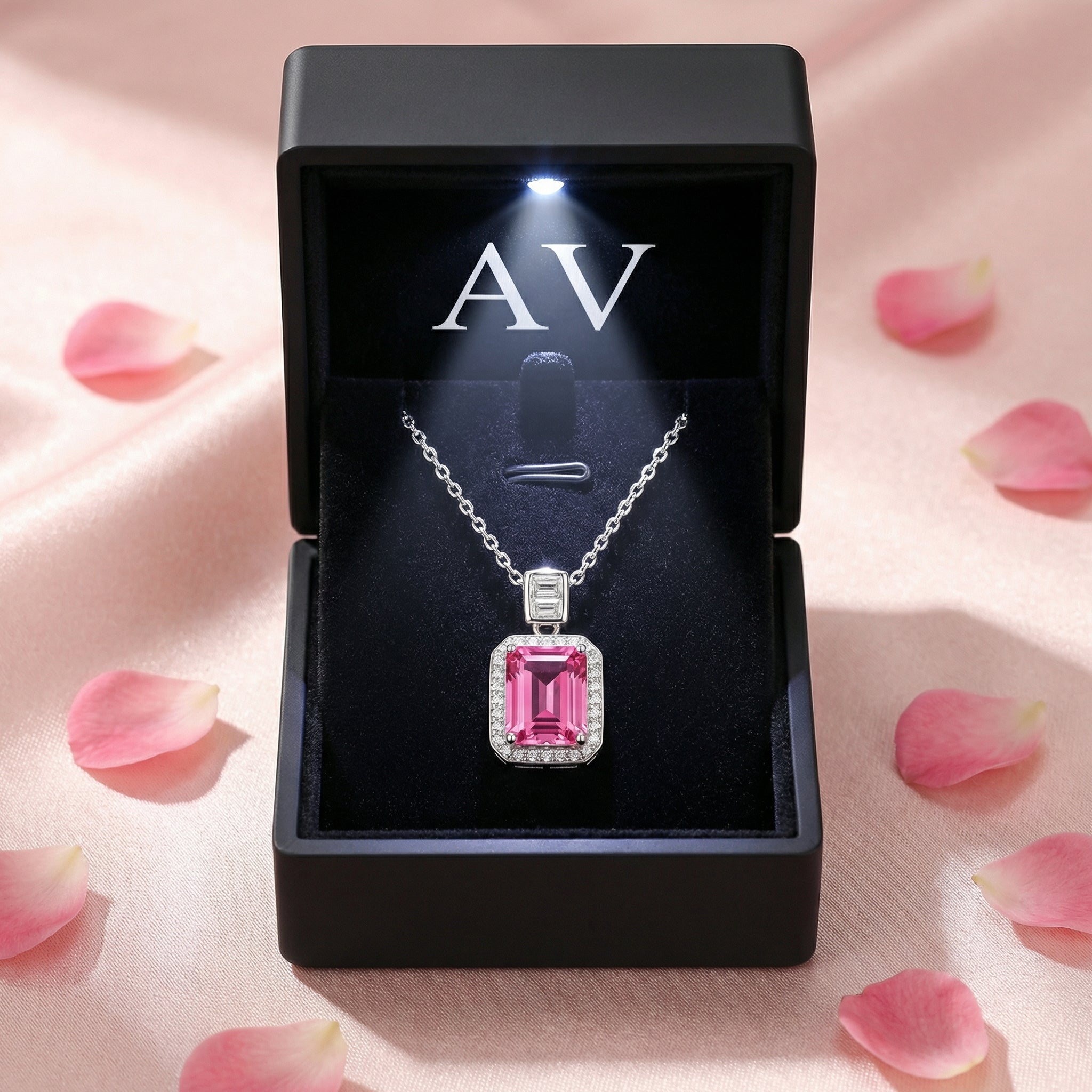 Sterling silver pink tourmaline necklace presented in a black lighted gift box surrounded by rose petals.