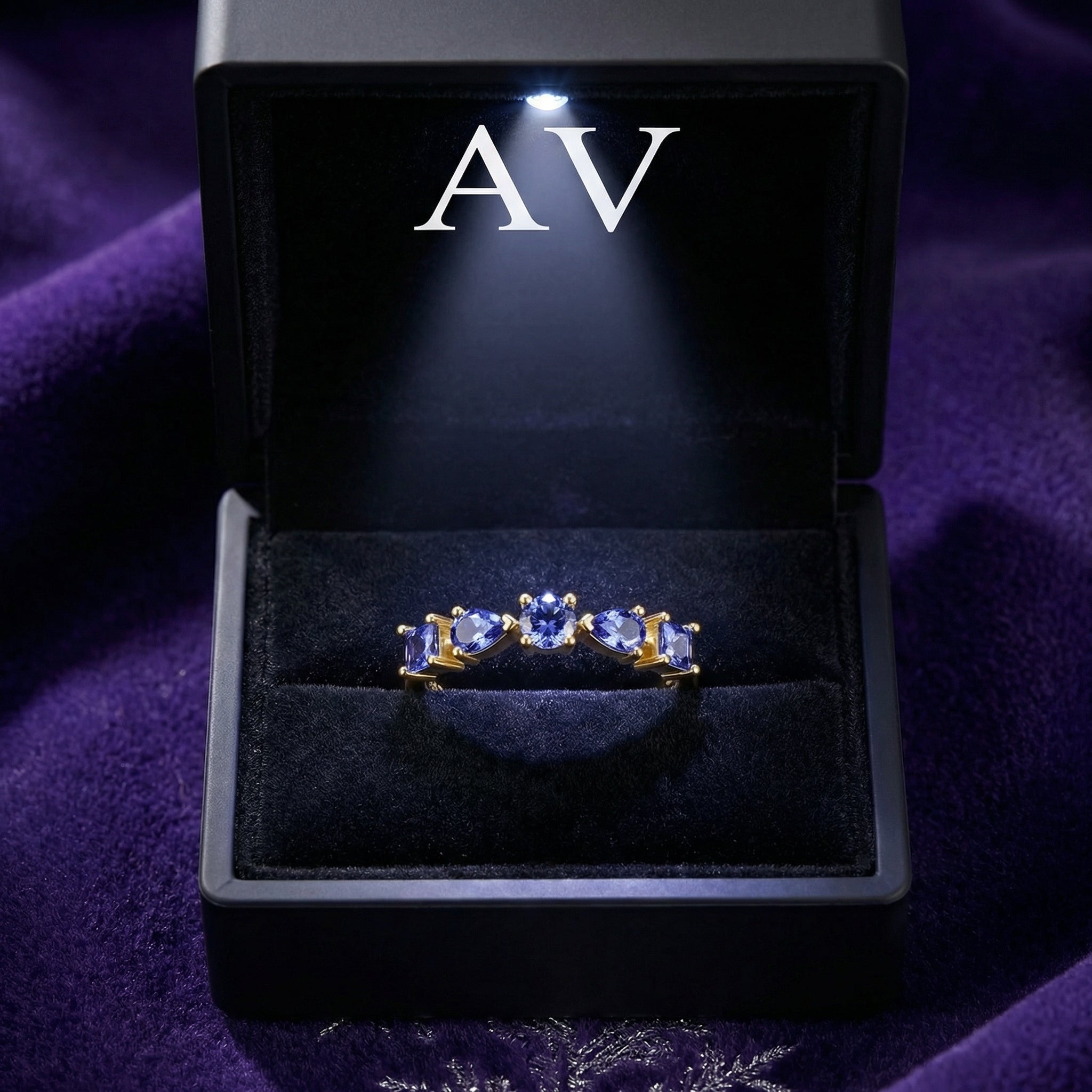 18K gold vermeil Nerisara cascade ring with simulated tanzanite stones in a lighted black jewelry presentation box.