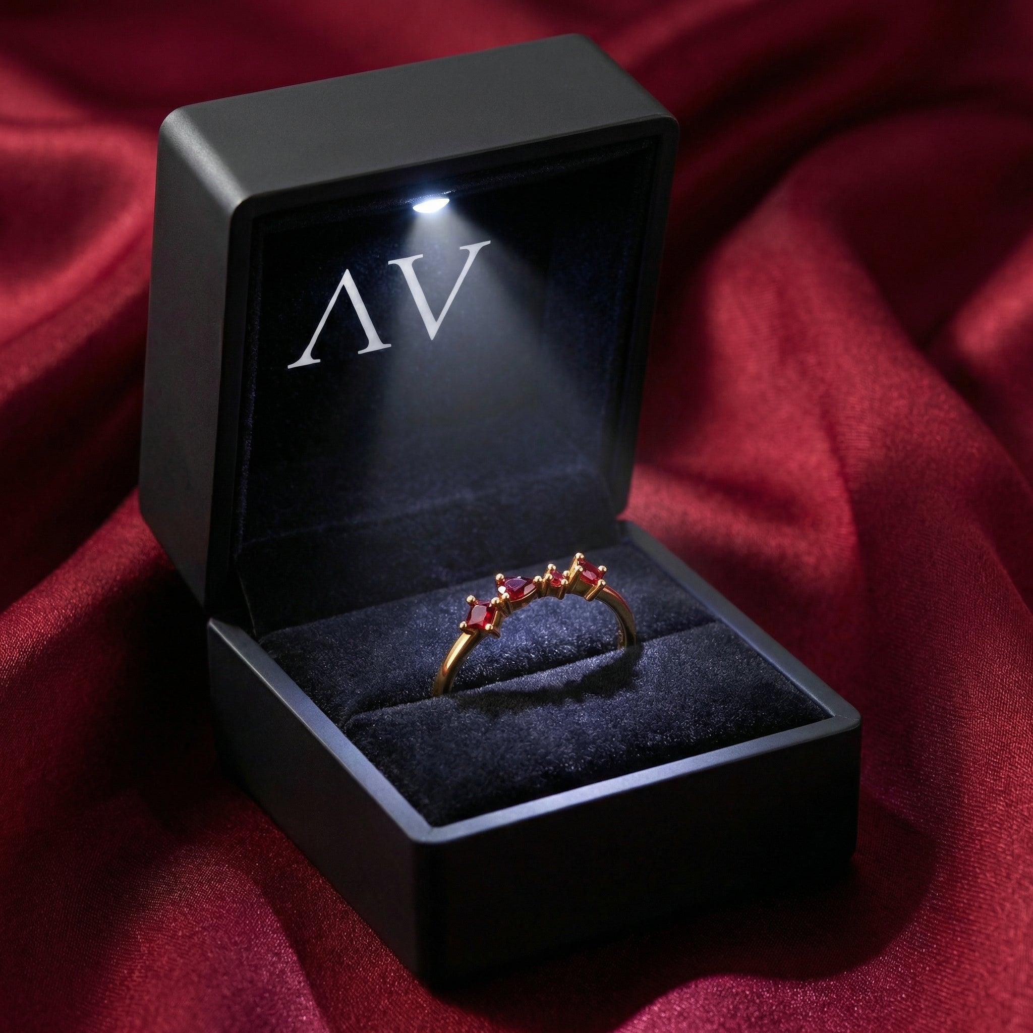 Julianna cluster ring in 18K gold vermeil with simulated rubies inside a black LED-lit jewelry box.