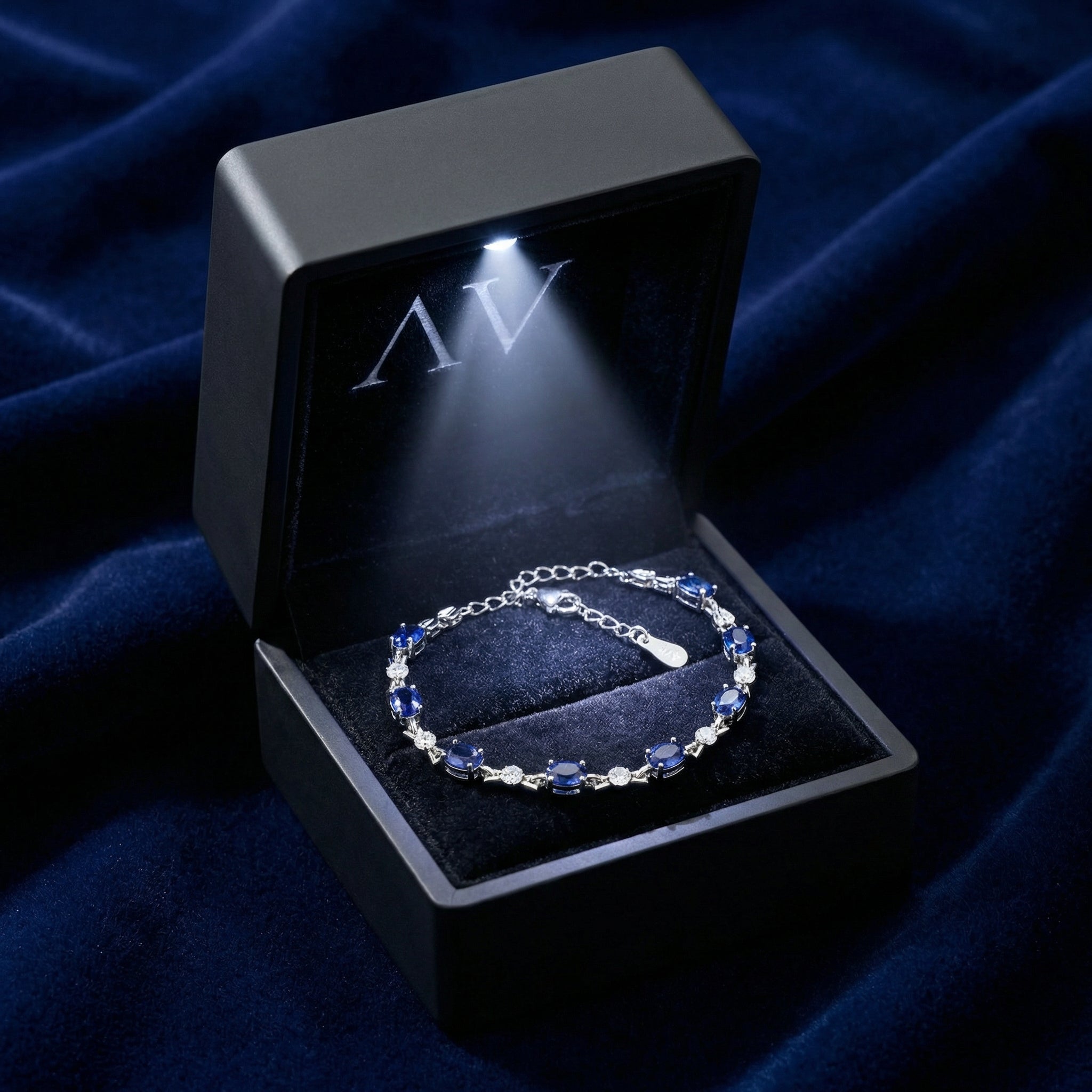 Sterling silver simulated sapphire tennis bracelet inside a black LED-lit jewelry presentation box.