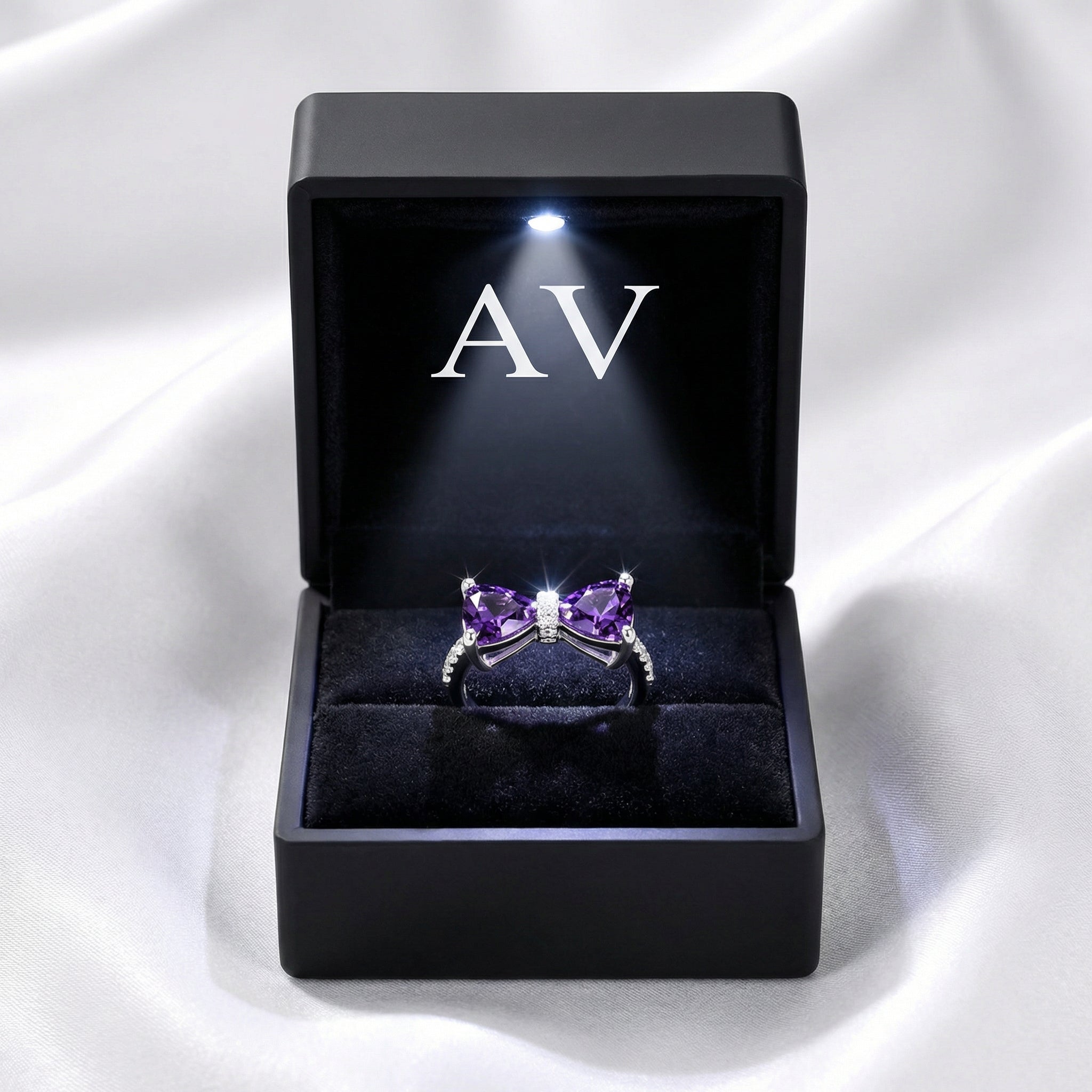Purple simulated amethyst bow ring in S925 sterling silver inside a black LED-lit gift box.