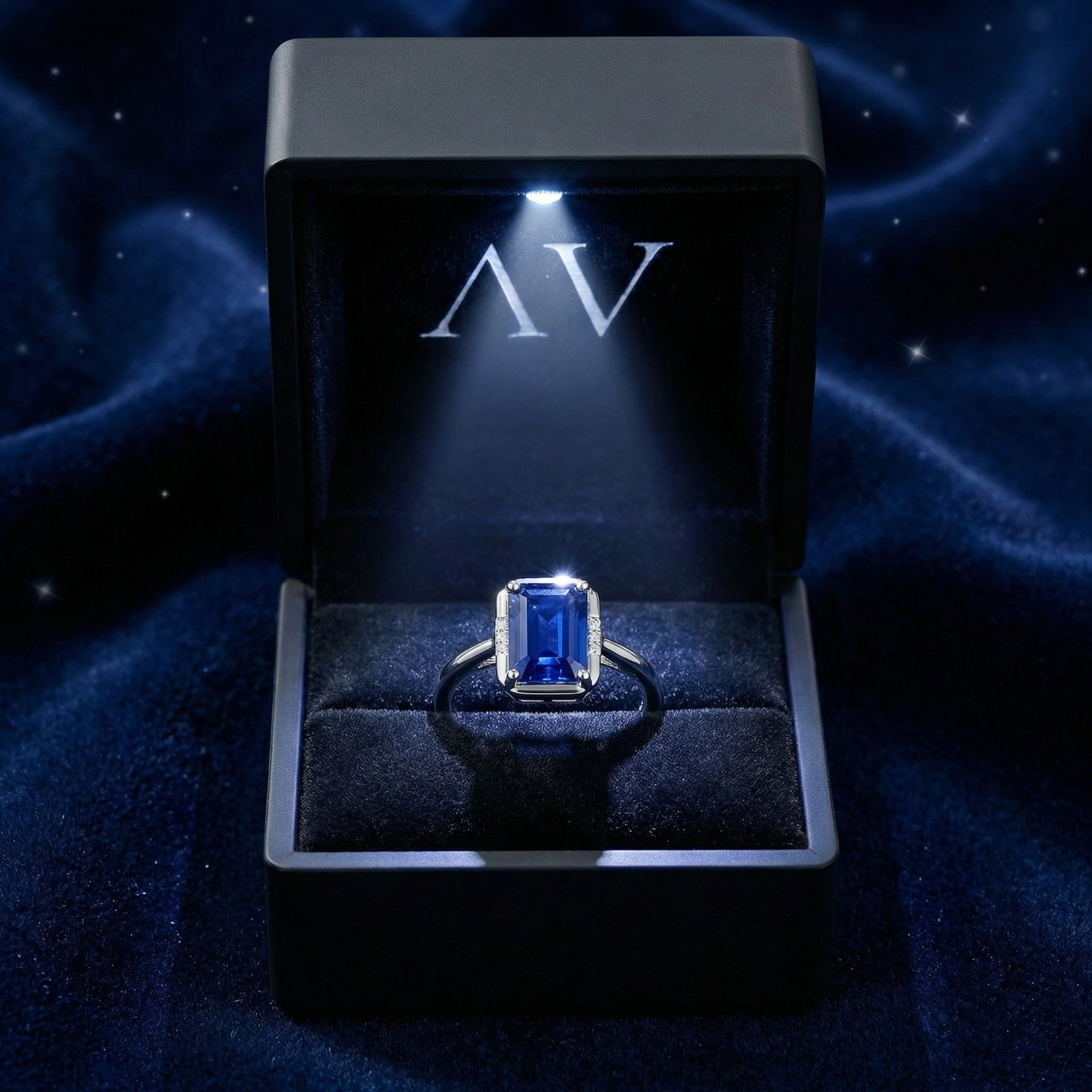 Emerald cut blue sapphire sterling silver ring presented in a black LED-lit jewelry gift box.