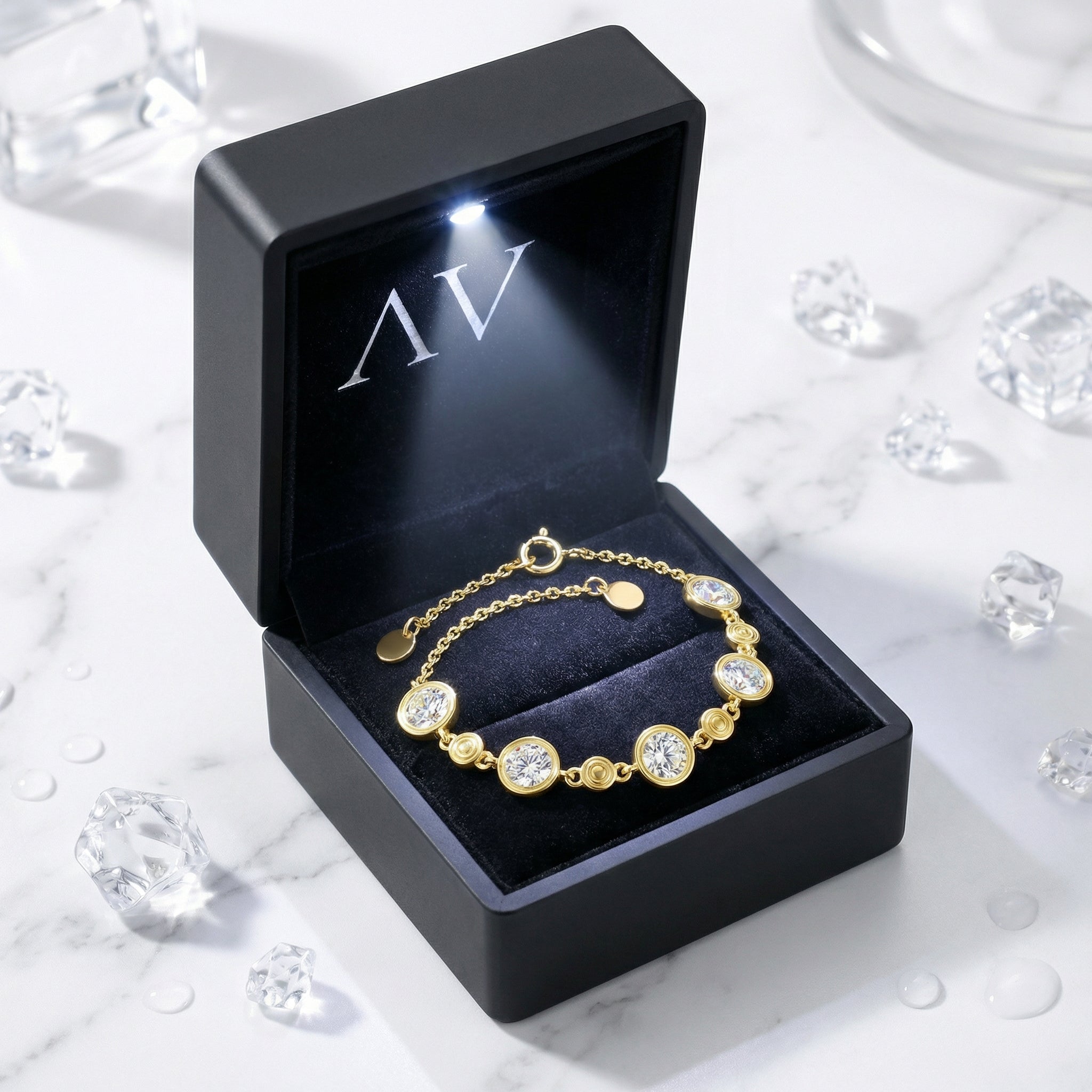 Gold Mirellia station bracelet inside a black LED-lighted jewelry gift box on a marble background.