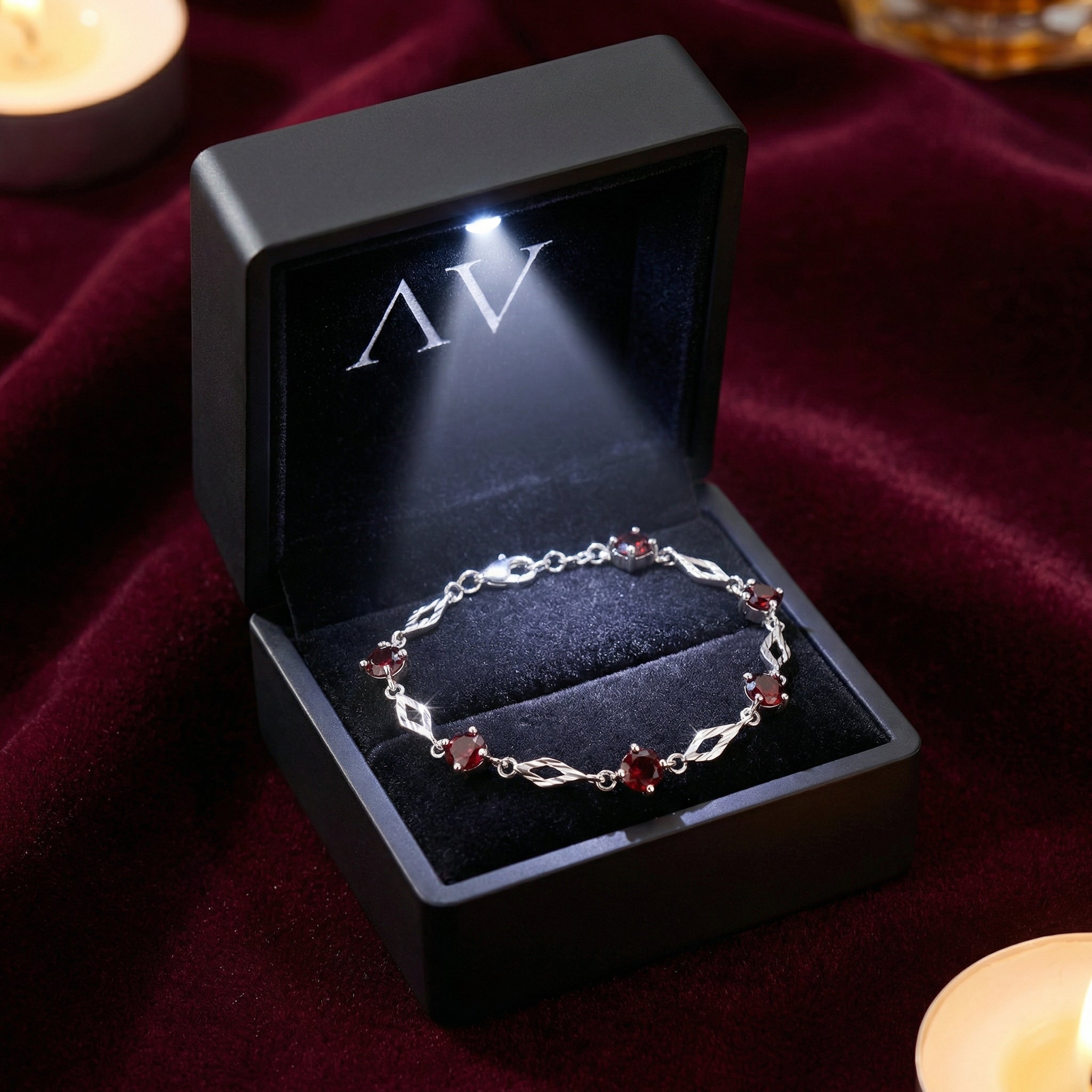 Sterling silver garnet station bracelet in a black LED-lit presentation box on red velvet.