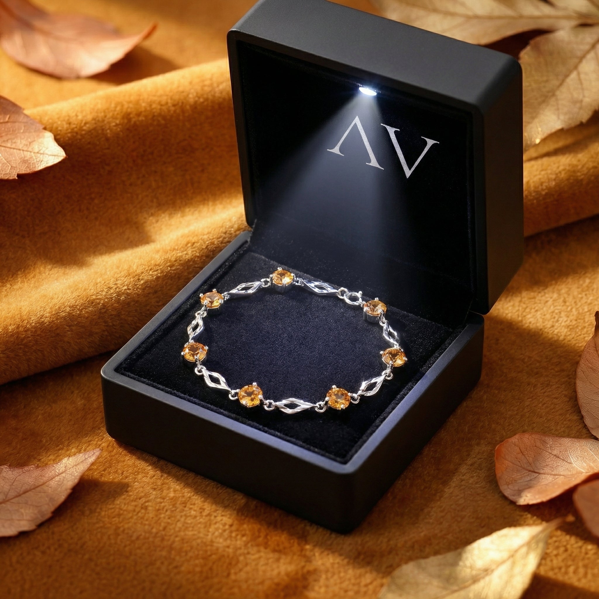 Sterling silver Zenara station bracelet with simulated topaz stones presented in a black LED-lit jewelry gift box.